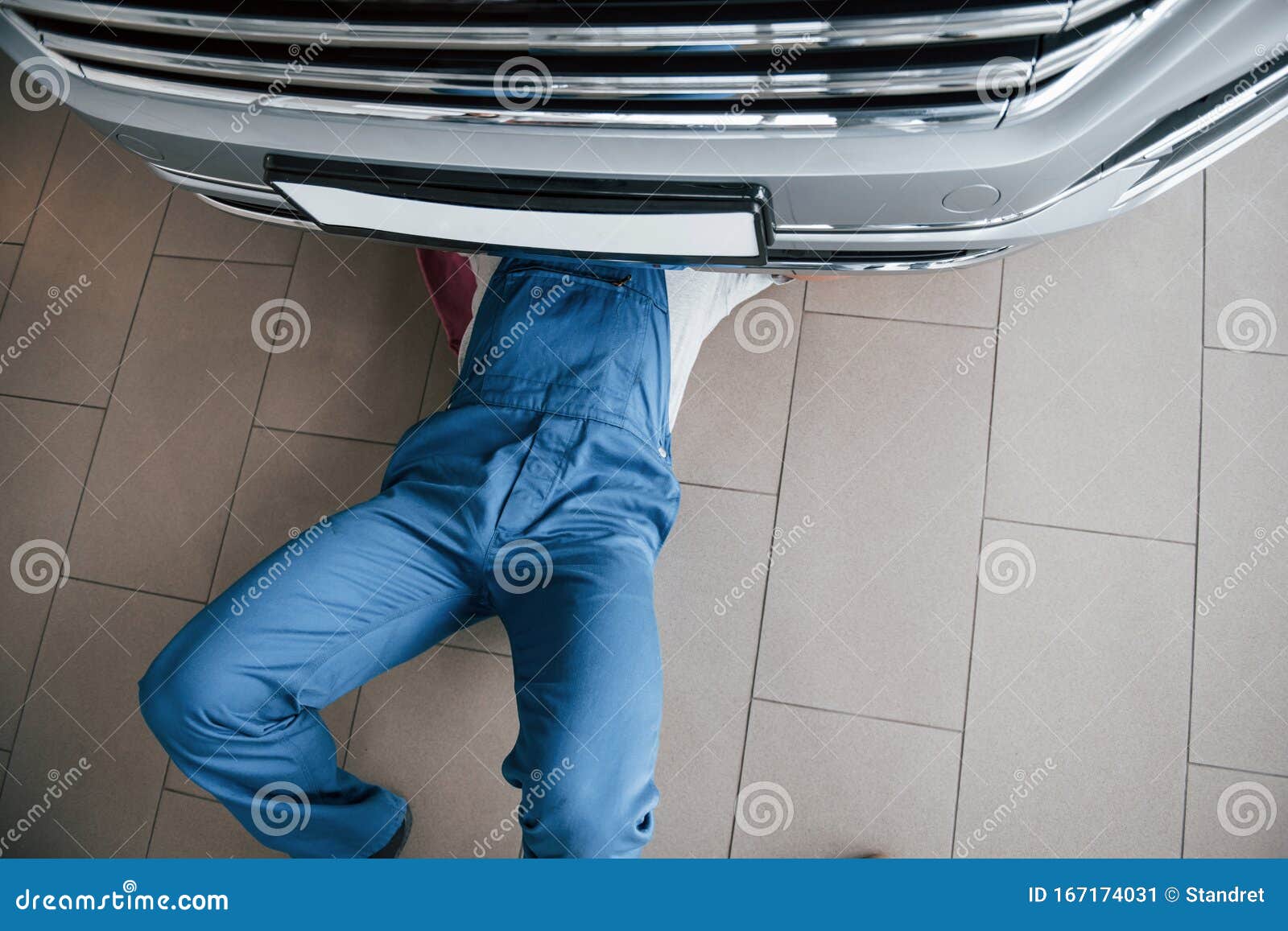 top view. man in blue uniform works with broken car. making repairings