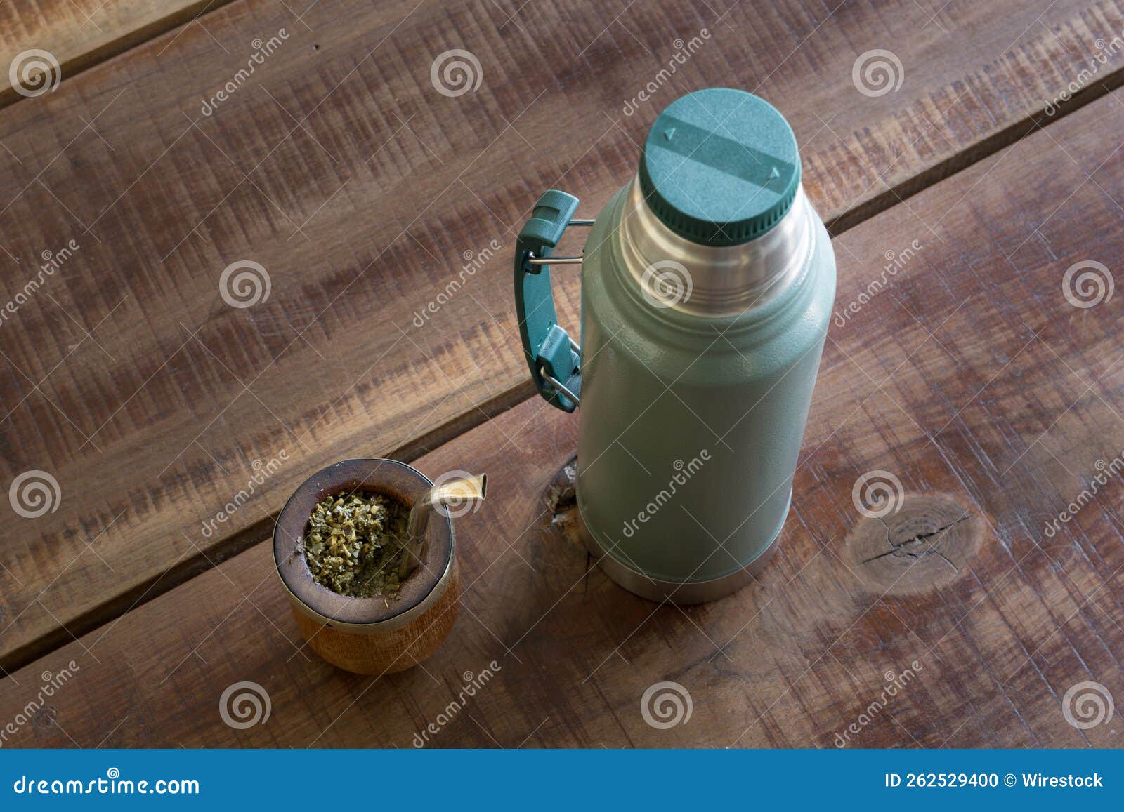 top view of mate caffeine-rich infused drink in a palo santo wood cup next to a thermos bottle