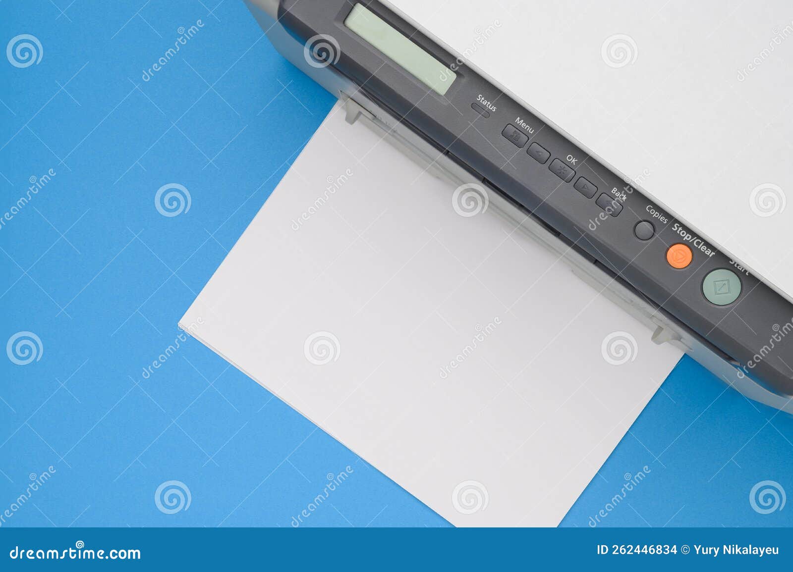 Top View of an Office Printer and a Blank Sheet of Paper on a Blue