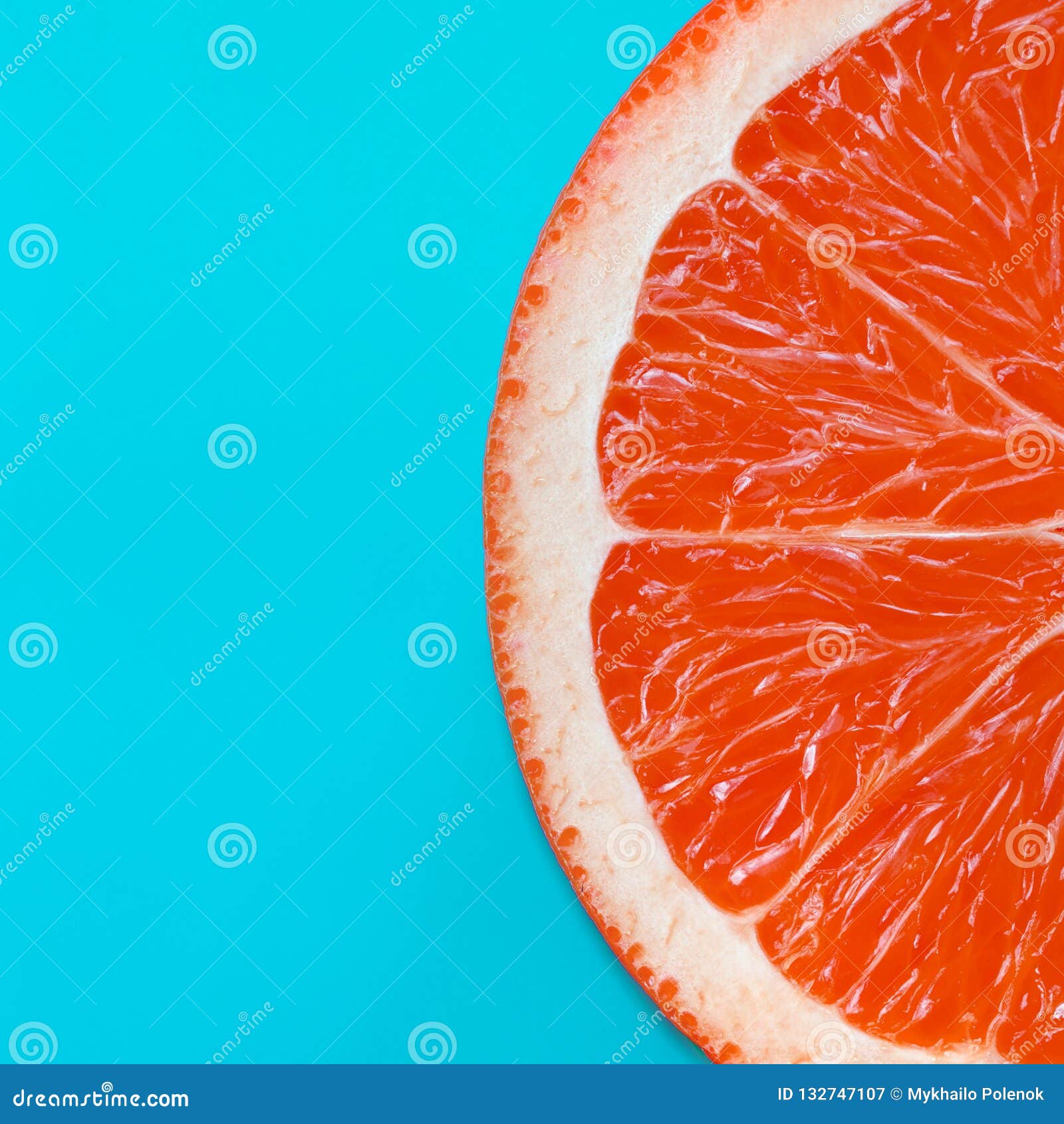 top view of an one grapefruit slice on bright background in blue color. a saturated citrus texture image