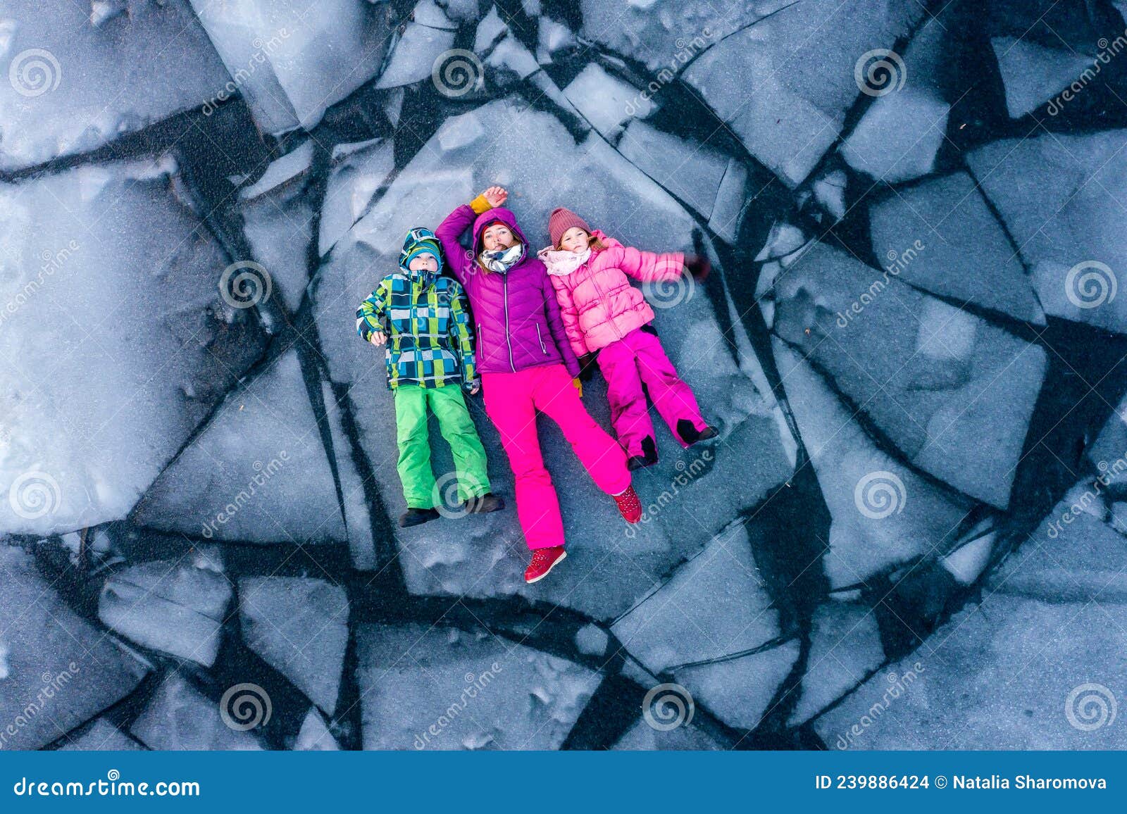 top view of people lying on ice alone. woman and children in bright clothes on broken ice block in water. winter cracked