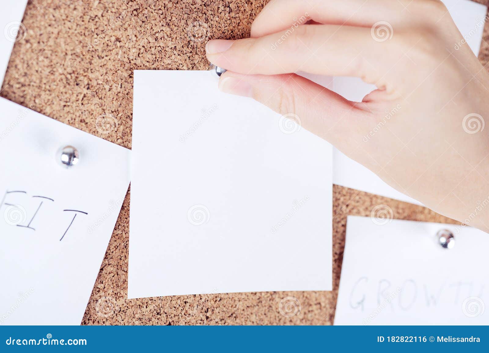 top view of person hand attaching reminder sticky note to cork board. cortical plank with sheets of paper. empty place