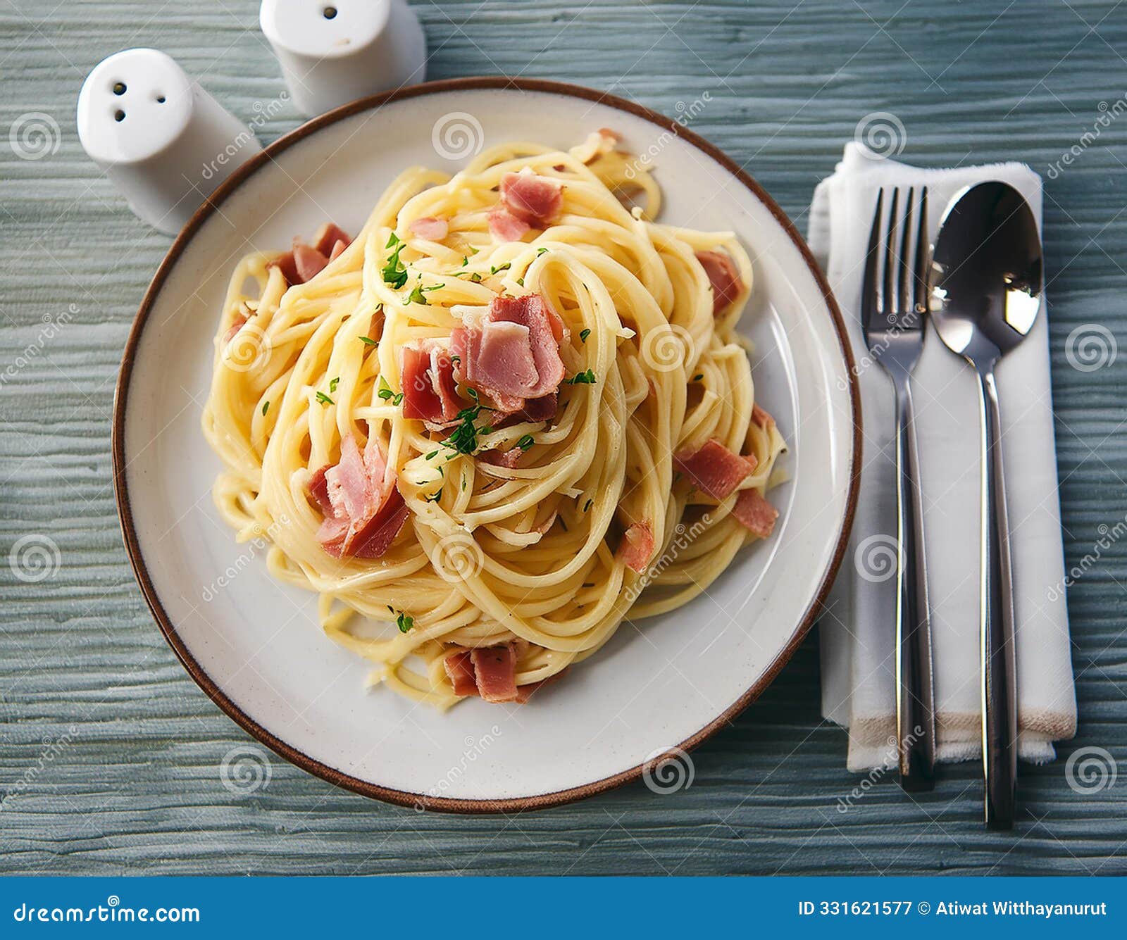 top view plate of spaghetti ham with cabonara cream source with fork and spoon on table background