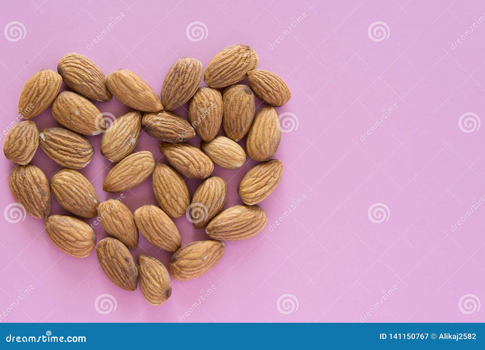 Top View of Raw Almonds in Heart Shape on Pink Background Stock Image