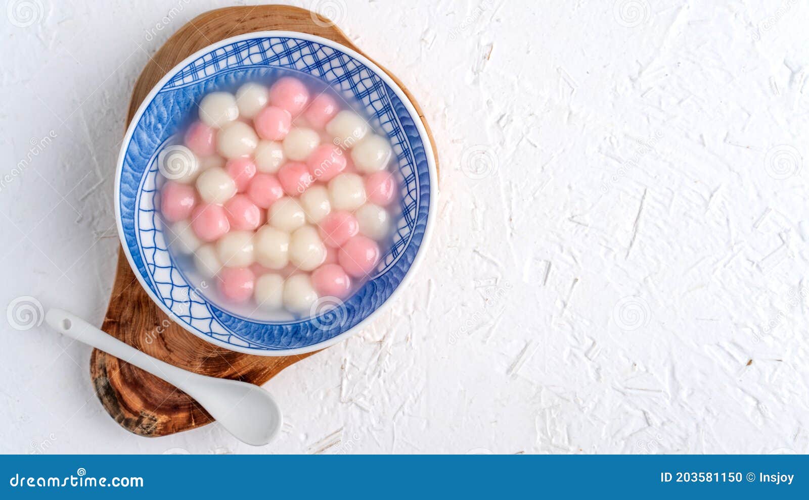 top view of red and white tangyuan in blue bowl on white background for winter solstice
