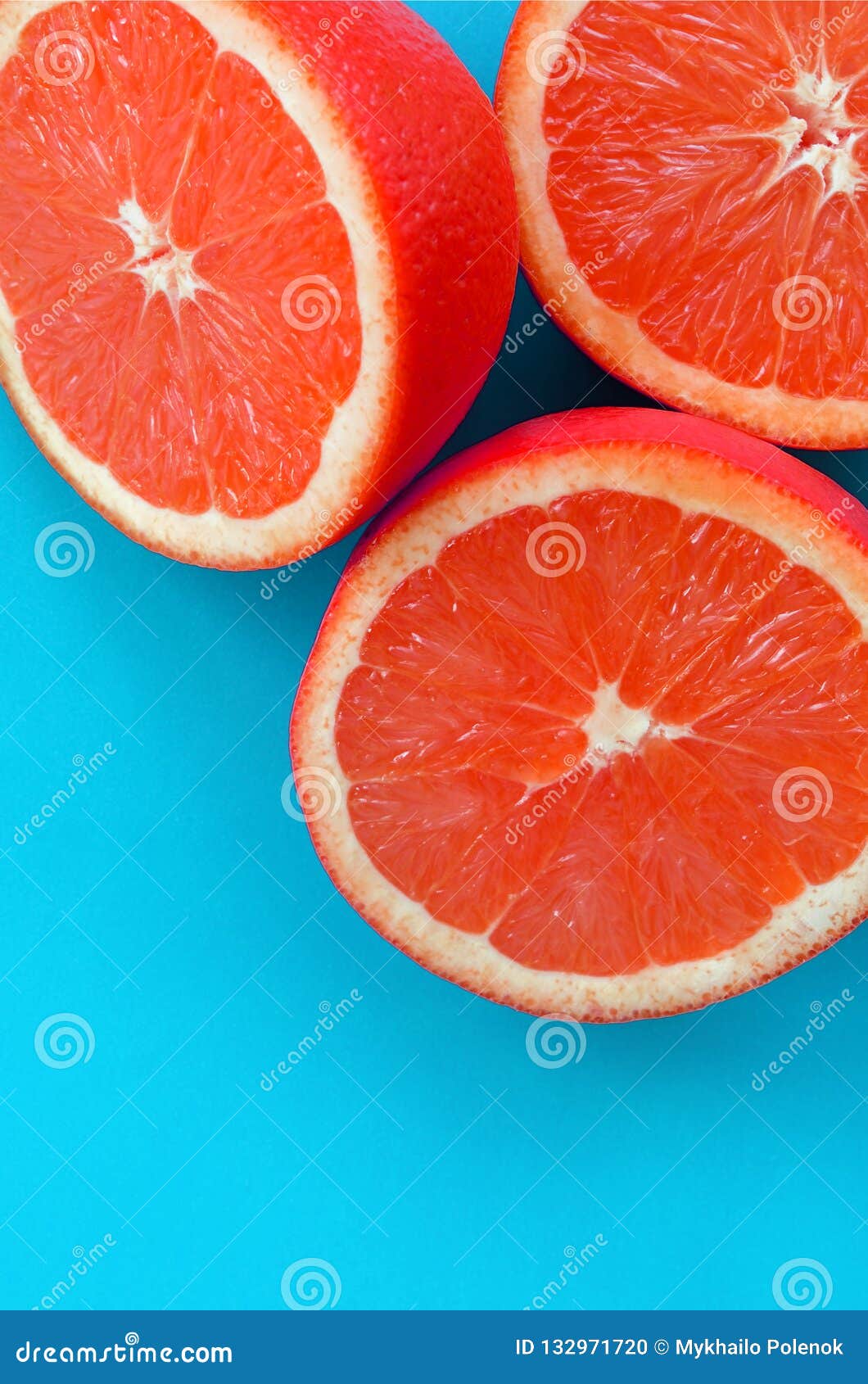 top view of a several grapefruit slices on bright background in blue color. a saturated citrus texture image