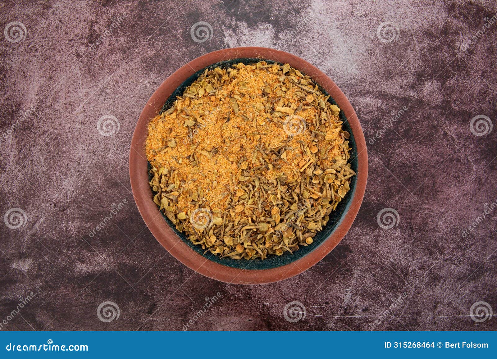 top view of a small bowl filled with cajun blackened seasoning on a red mottled tabletop