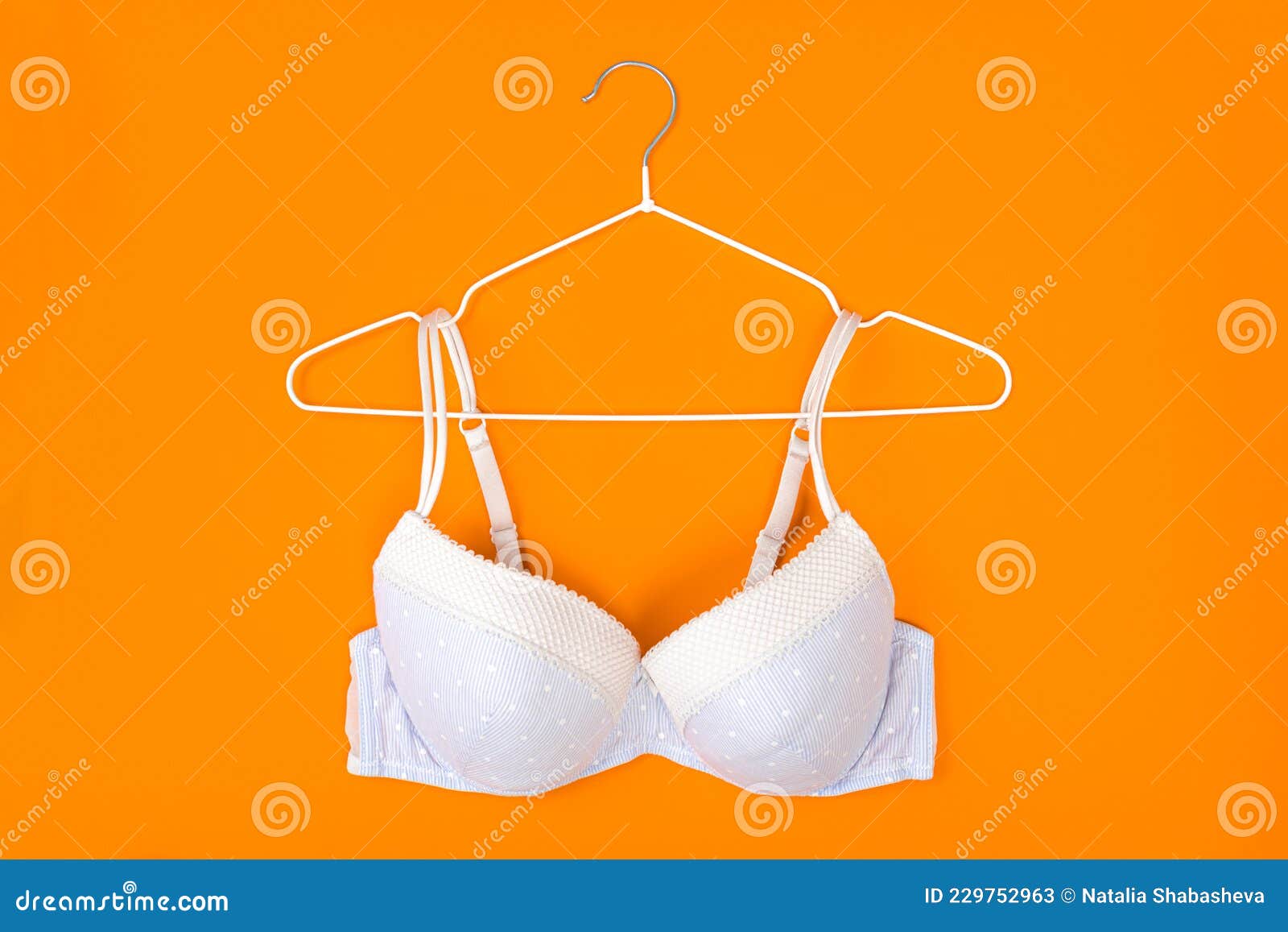 Top View of Stylish Women Bra on White Hanger on Orange Background
