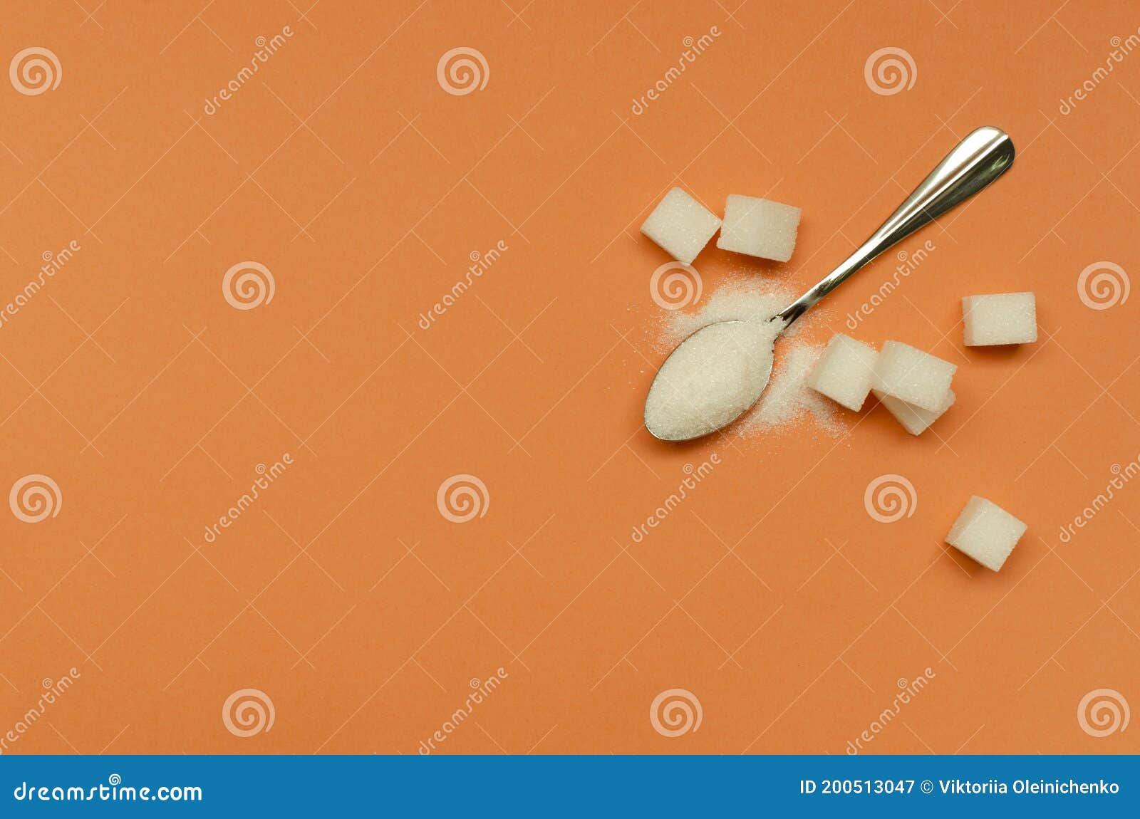 top view of teaspoon and sugar on the orange surface.empty space