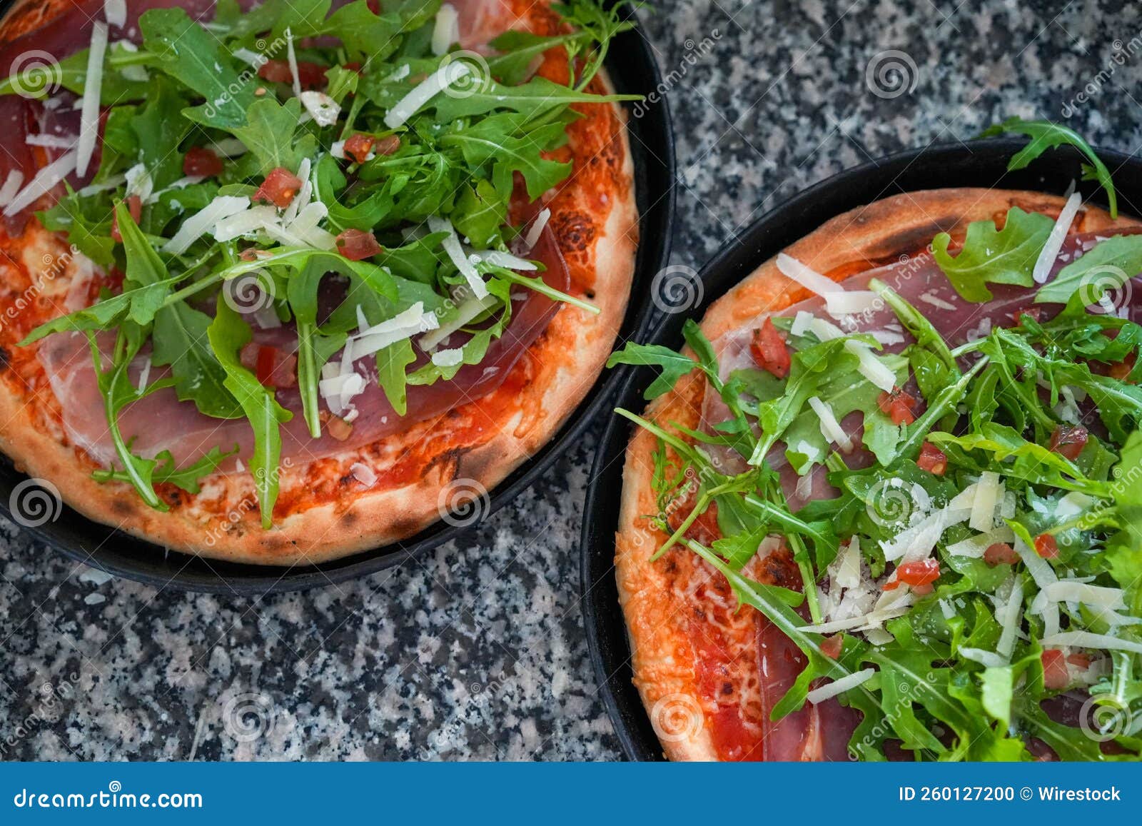 Top View of Two Small Delicious Pizzas with Arugula on a Gray Marble
