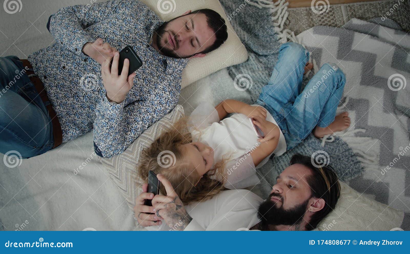 Two Men and Little Girl Lying and Using Smartphones Stock Video photo
