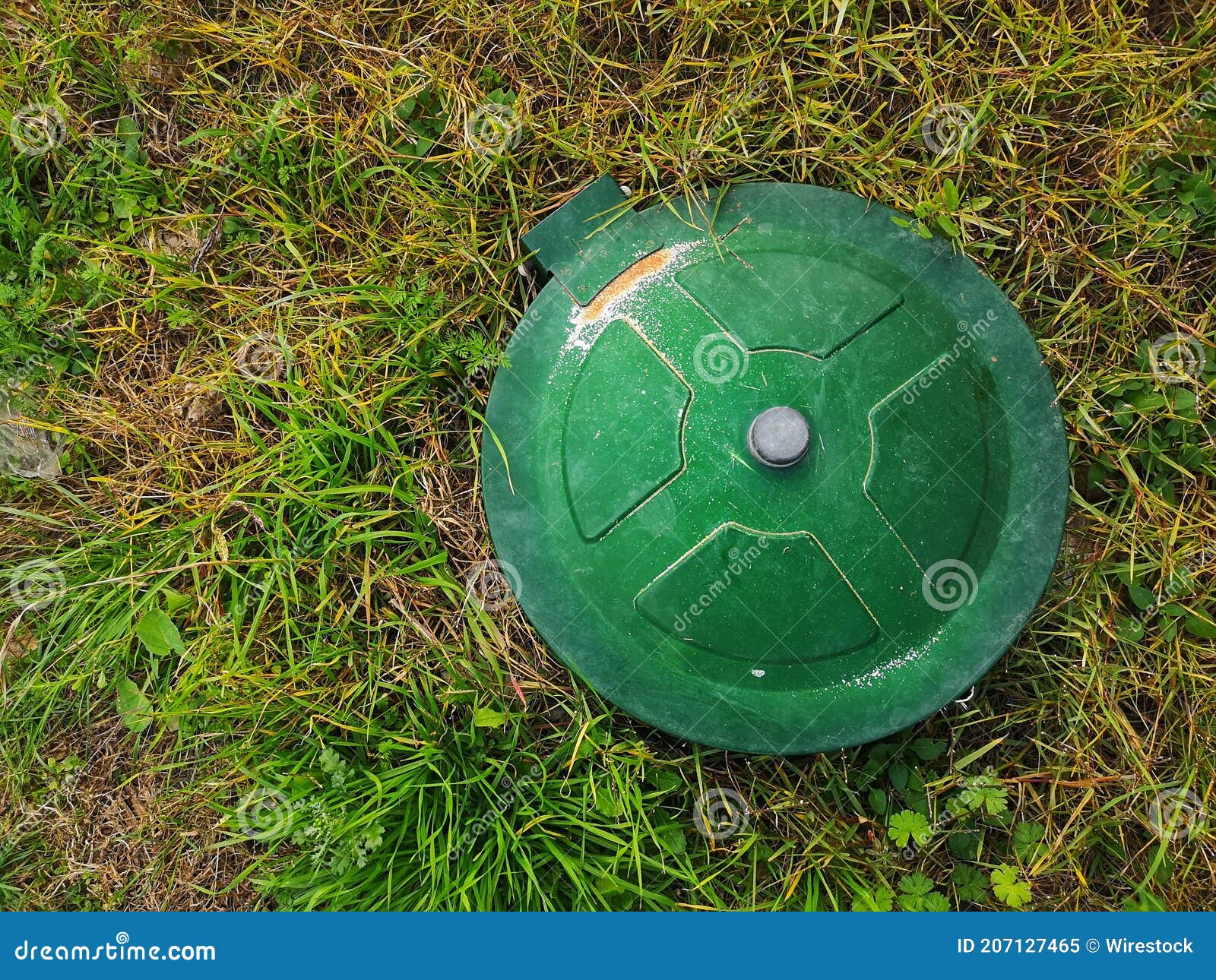 Top View of an Underground Gas Tank Cap in a Meadow Under the Sunlight