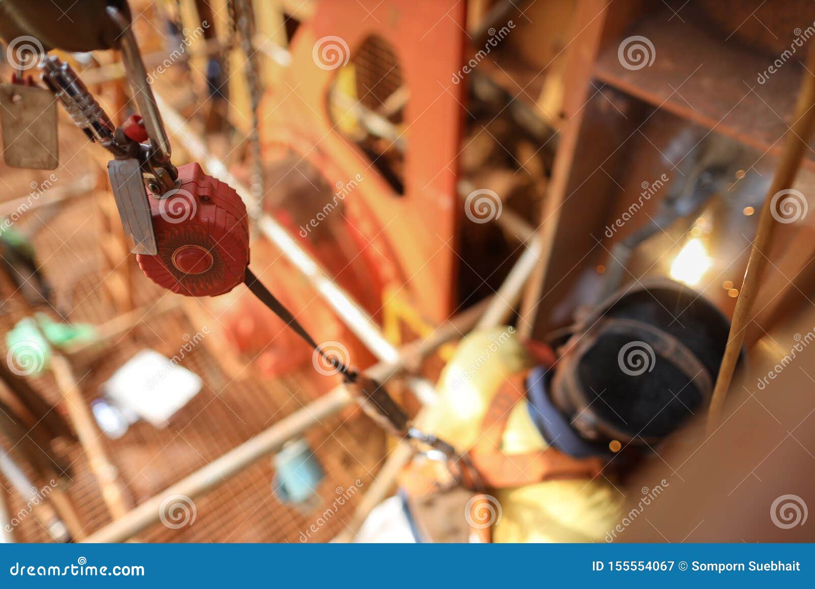 top view welder wearing safety helmet fall arrest harness using fall prevention system fall arrester retractable energy device
