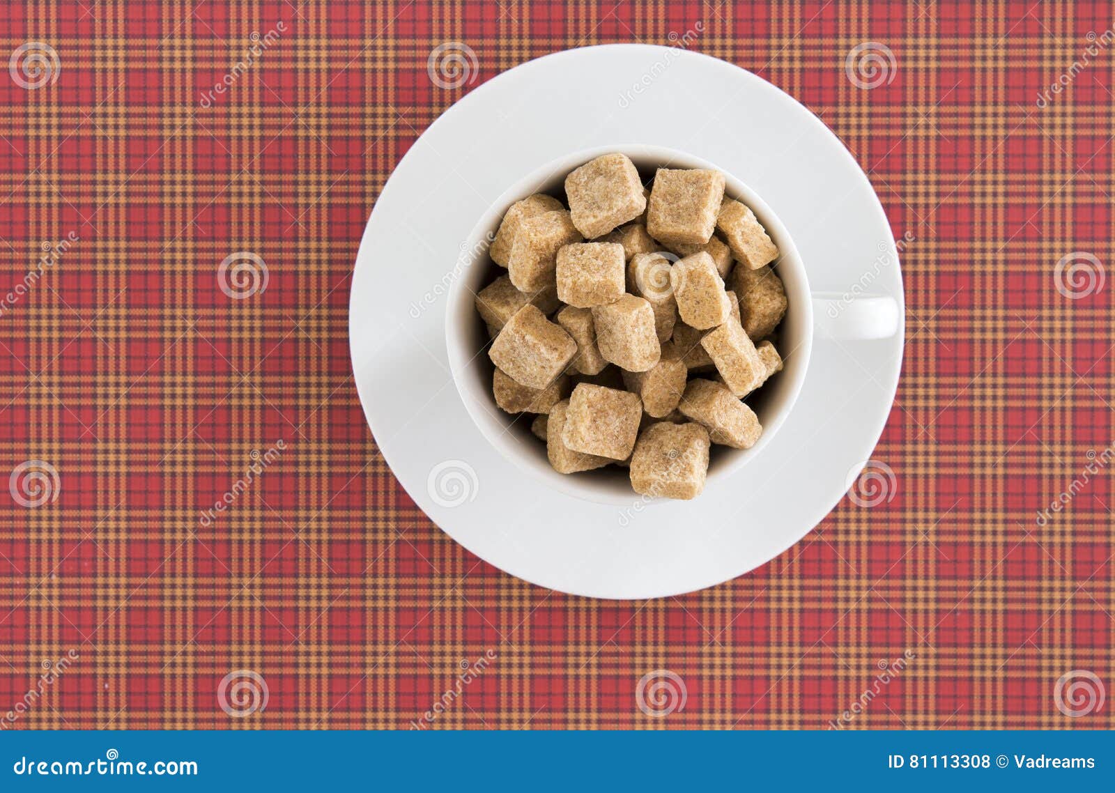 top view of white coffee or tea cup full brown sugar cubes on red squared background. diet unhealty sweet addiction