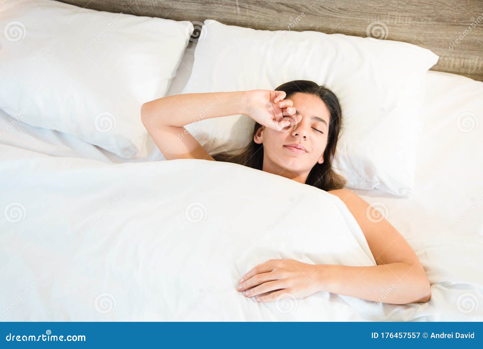 top view of woman waking up in her bed with white bed linens. healthy sleep and good disposition concept