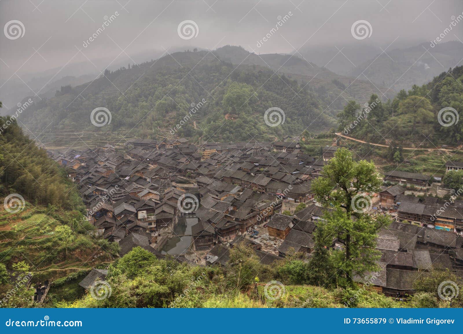 Top view on Zhaoxing Village ethnic minority, Guizhou, Chin. Zhaoxing Village, Guizhou Province, China - April 7, 2010: Panoramic picture of the ethnic minority settlements with wooden houses and tiled roofs, in the mountainous area of southwestern China.