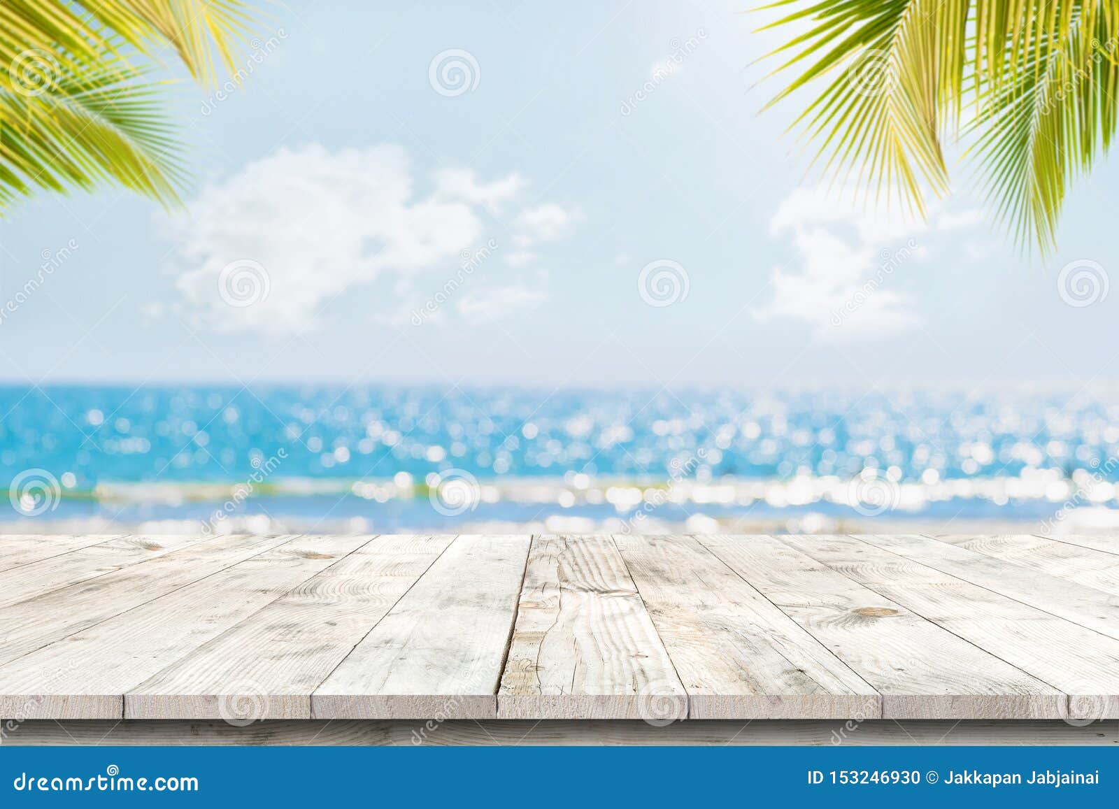 top of wood table with seascape and palm leaves, blur bokeh light of calm sea and sky at tropical beach background