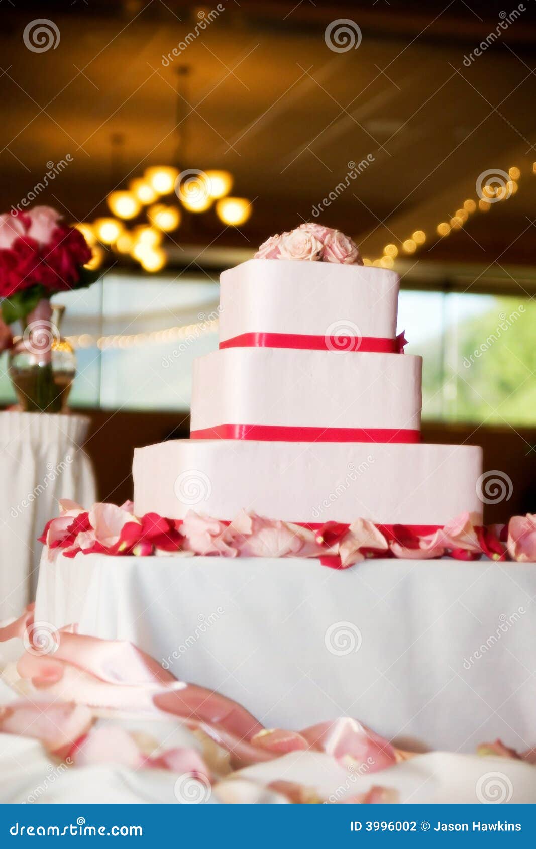 Torta di cerimonia nuziale con le rose. I bei tre hanno messo a strati la torta di cerimonia nuziale spruzzata con le rose