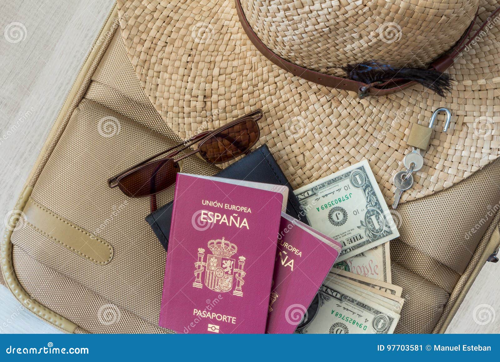 tourism travel concept. suitcase with female hat, sunglasses, spanish passports, dollars and padlock