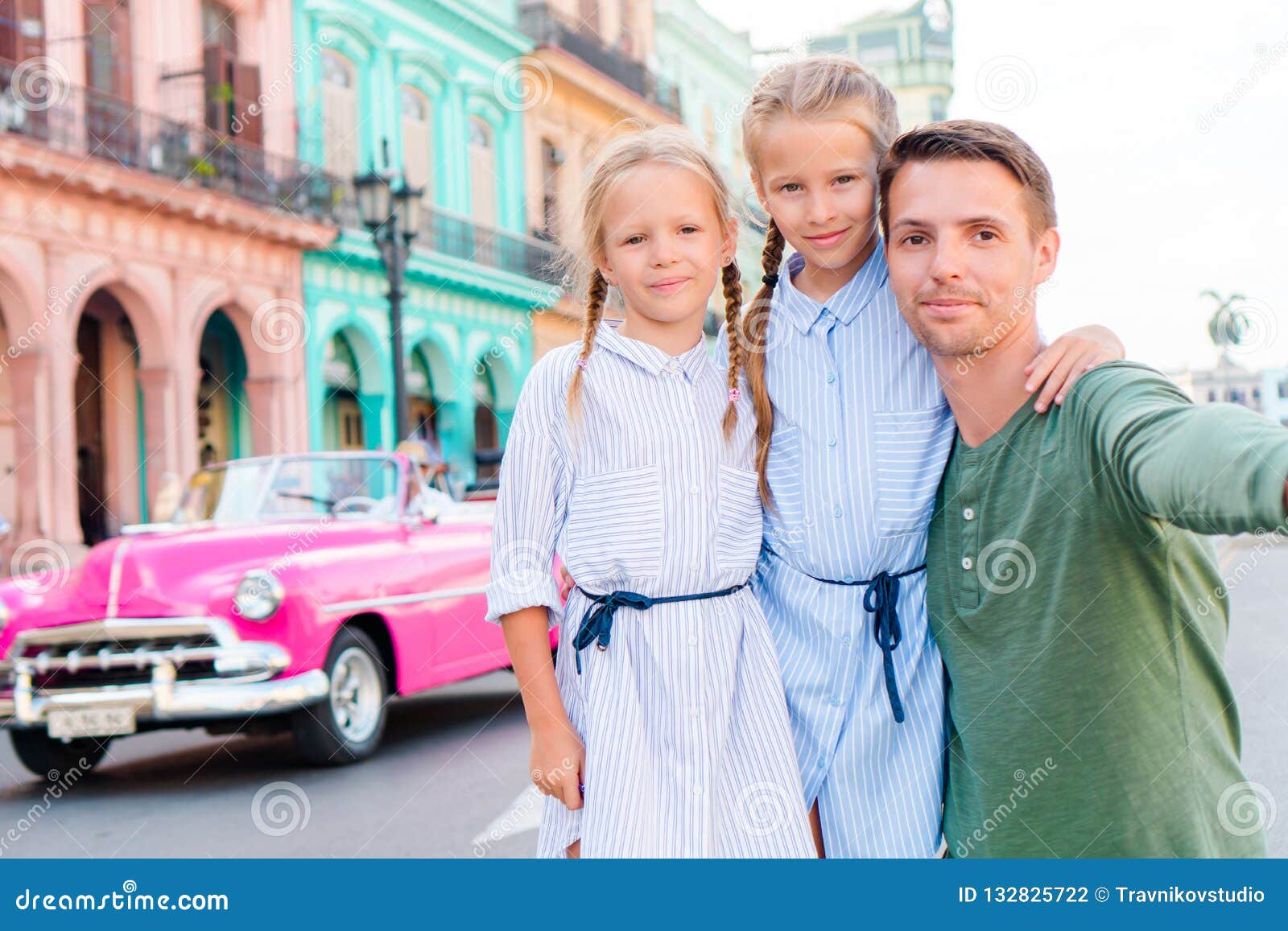 family in popular area in old havana, cuba. portrait of two kids and young dad outdoors on a street of havana