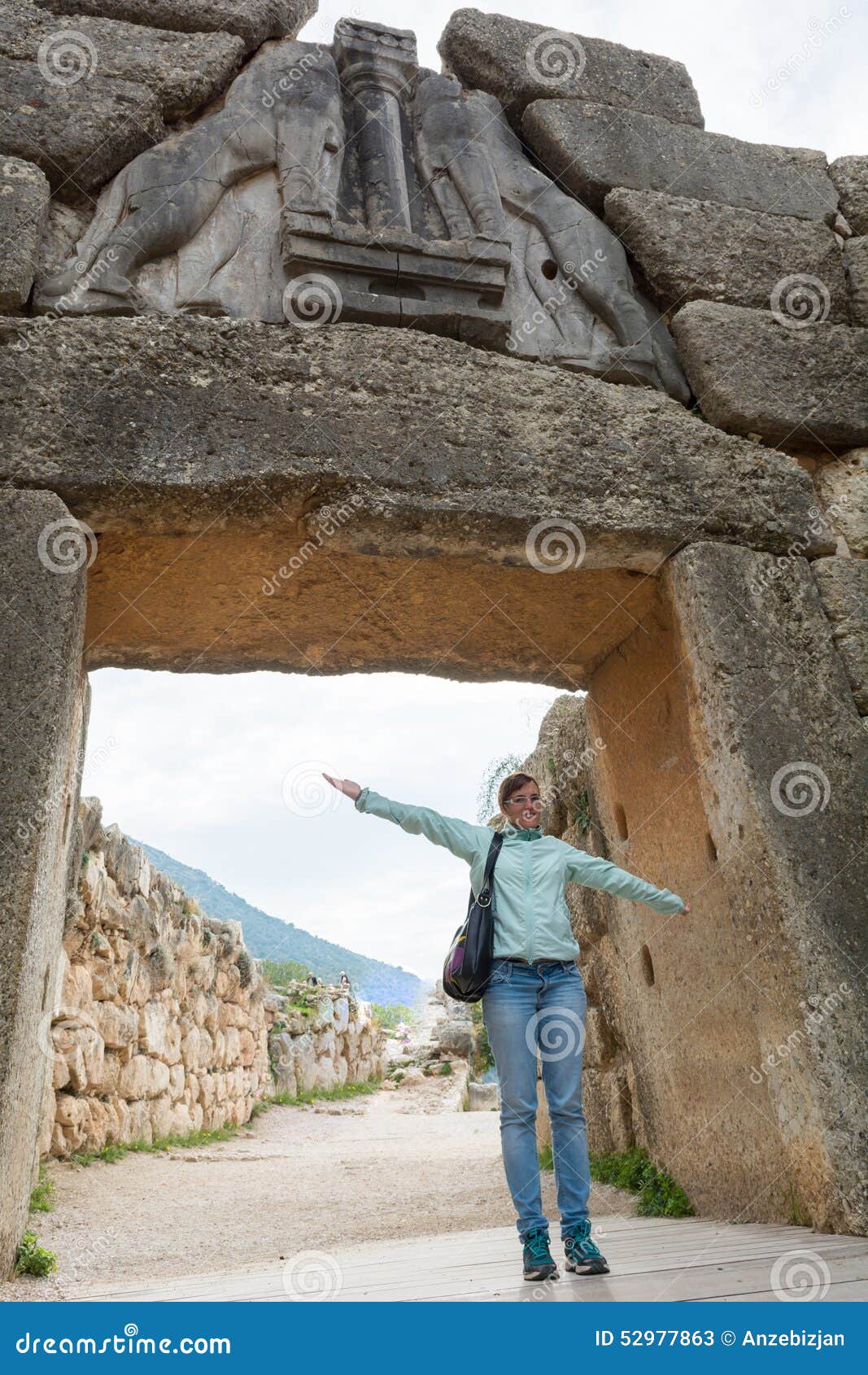 Tourist posing under famous Lion gate entrance. Tourist posing under famous Lion gate entrance to ancient Mycenae, Greece.