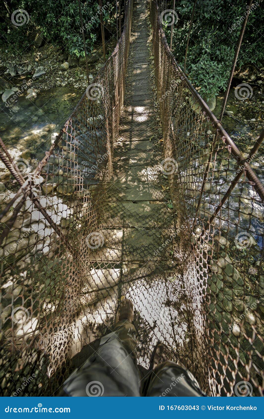 tourist stepping on a suspension bridge across rio colorado in rincon dela vieja volcano national park