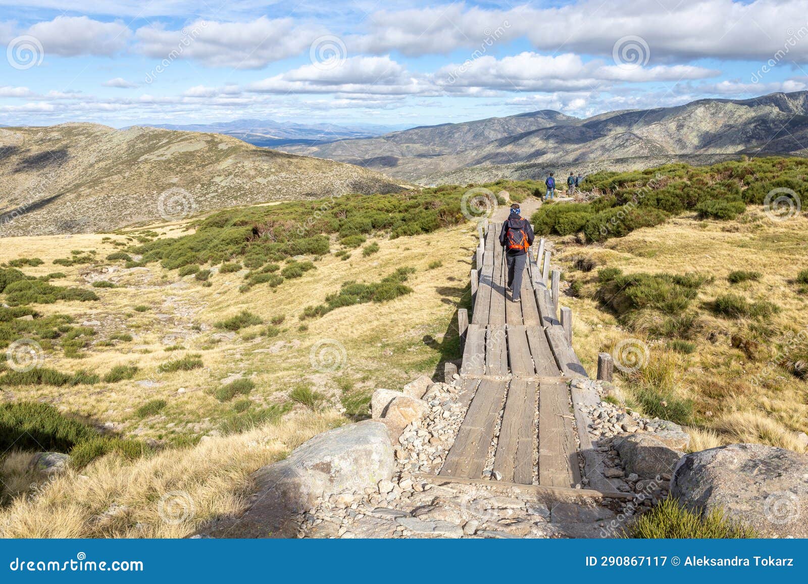 tourists hiking on wooden trail to the laguna grande de gredos lake, spain.