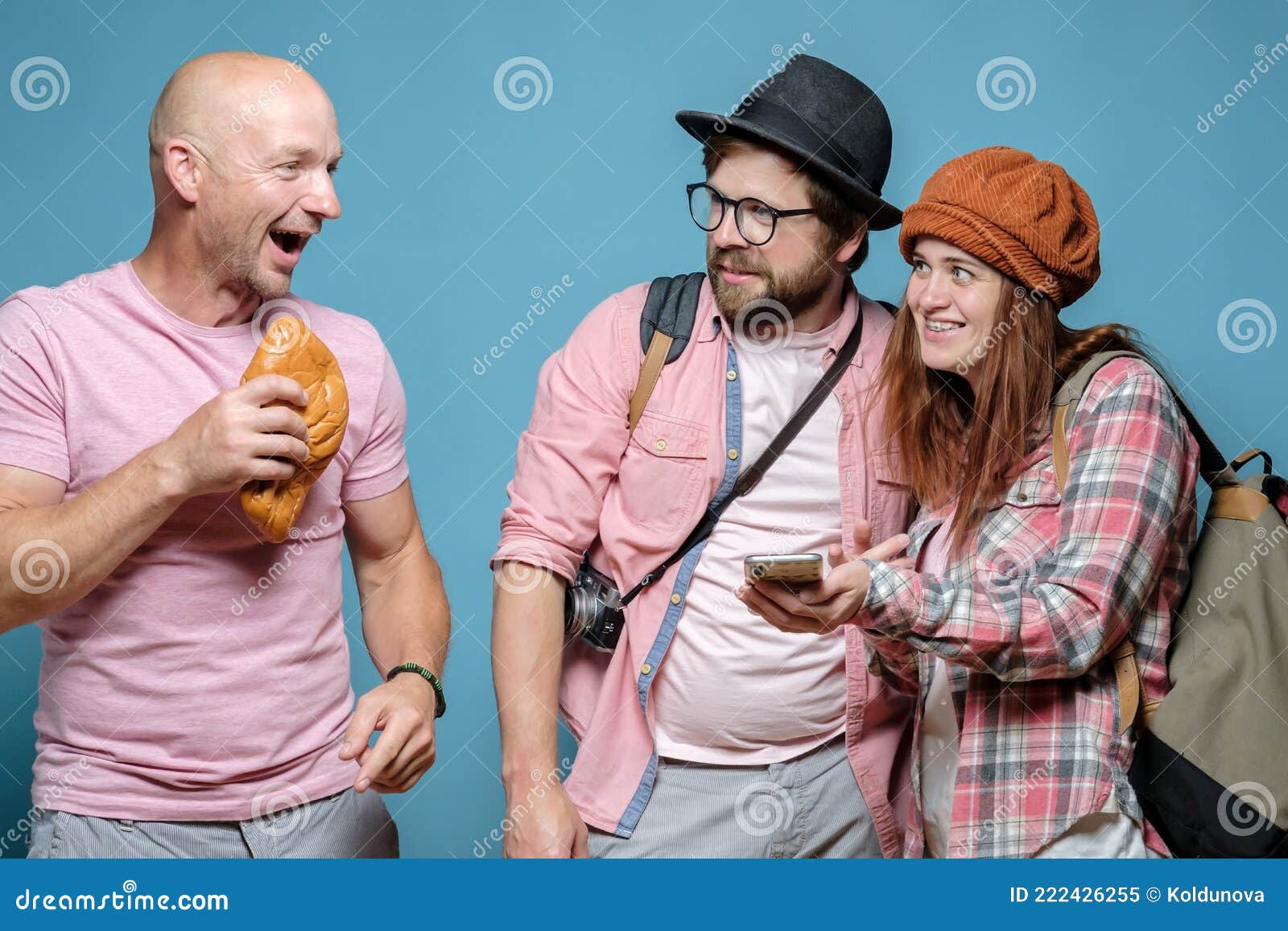 tourists, a smiling woman with a smartphone and an incredulous man ask the route from a cheerful local who holds a pie