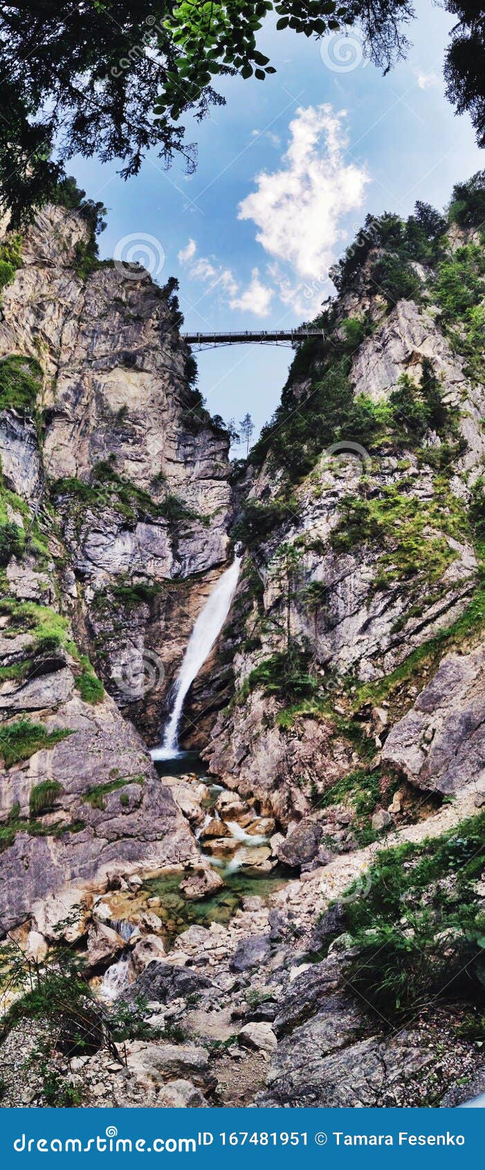 tourists stand on marienbruecke marie's bridge over waterfall near neuschwanstein castle