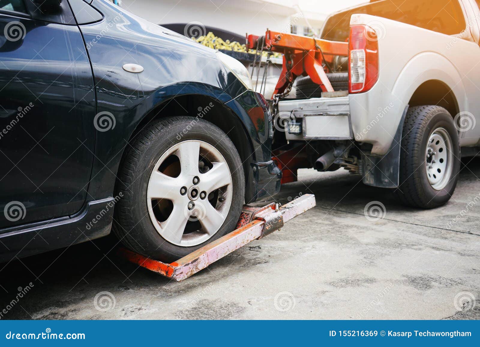 tow truck picking up and towing old broken down car on a roadside