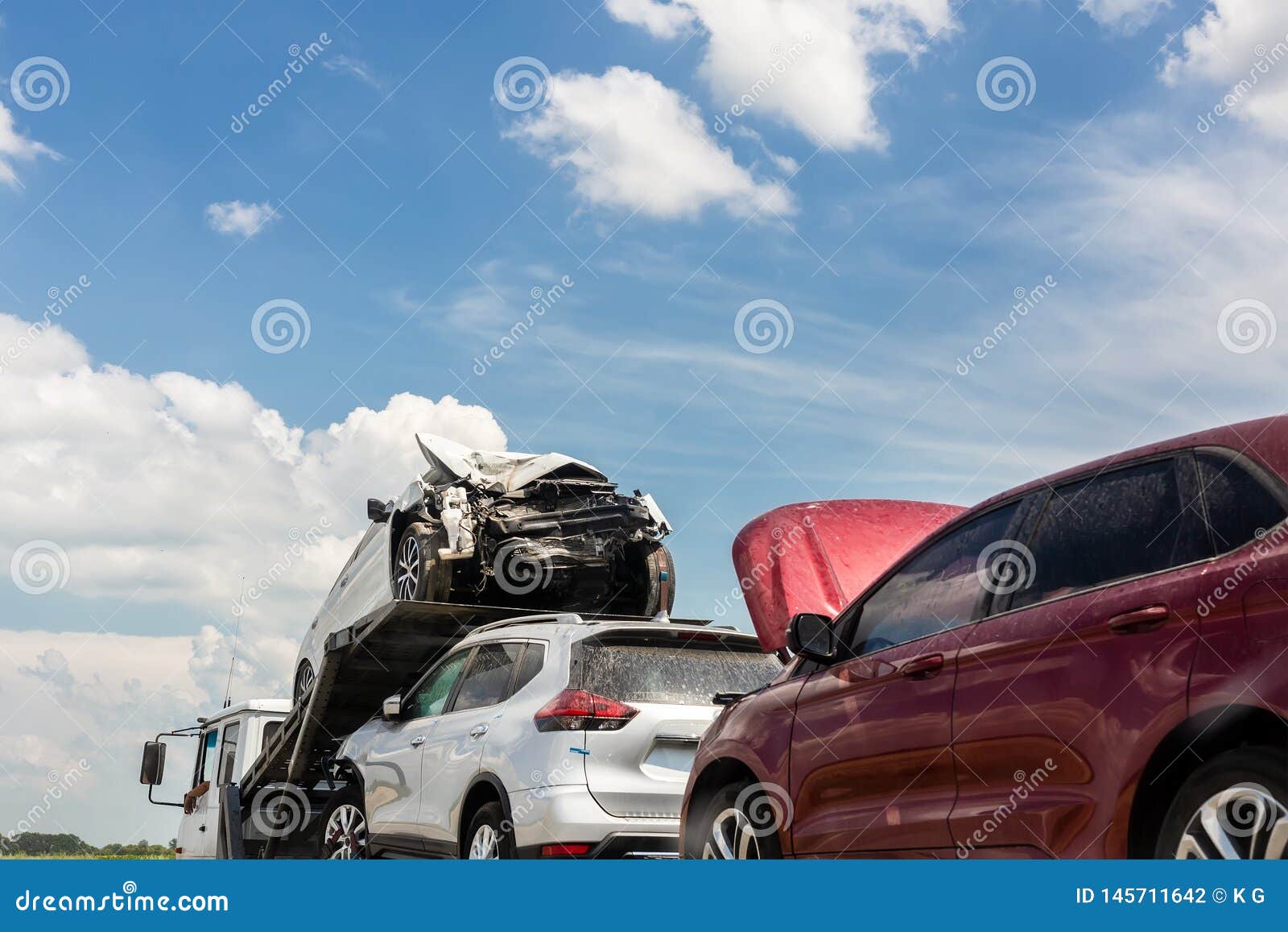 tow truck trailer on highway carrying three damaged cars sold on insurance car auctions for repair and recovery.  vehicles