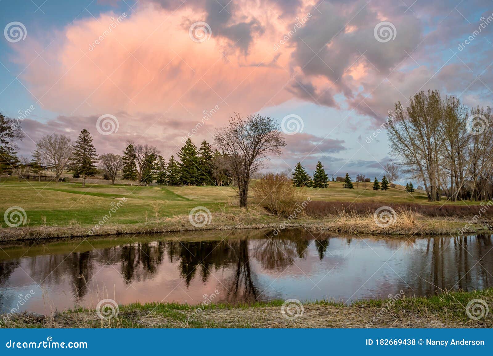 towering pink sunset cloud over a golf course in swift current, sk, canada