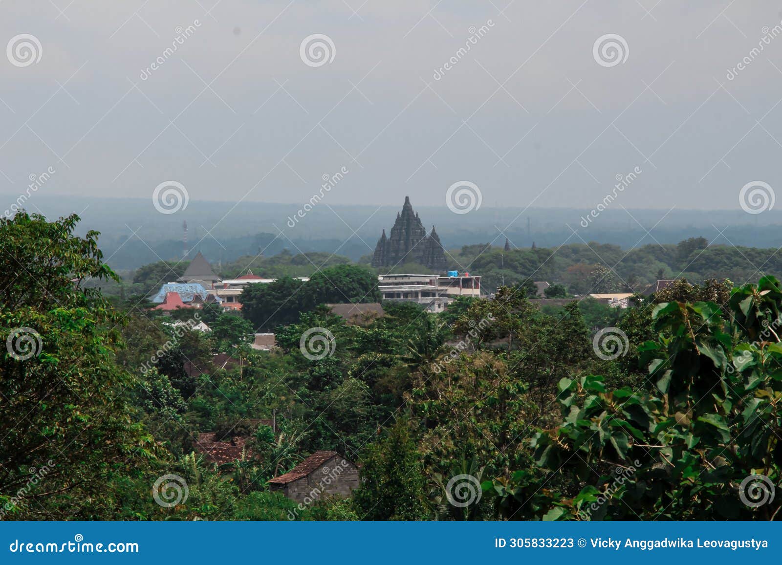 a towering temple seen from a distance, its height dominates the buildings and trees around it