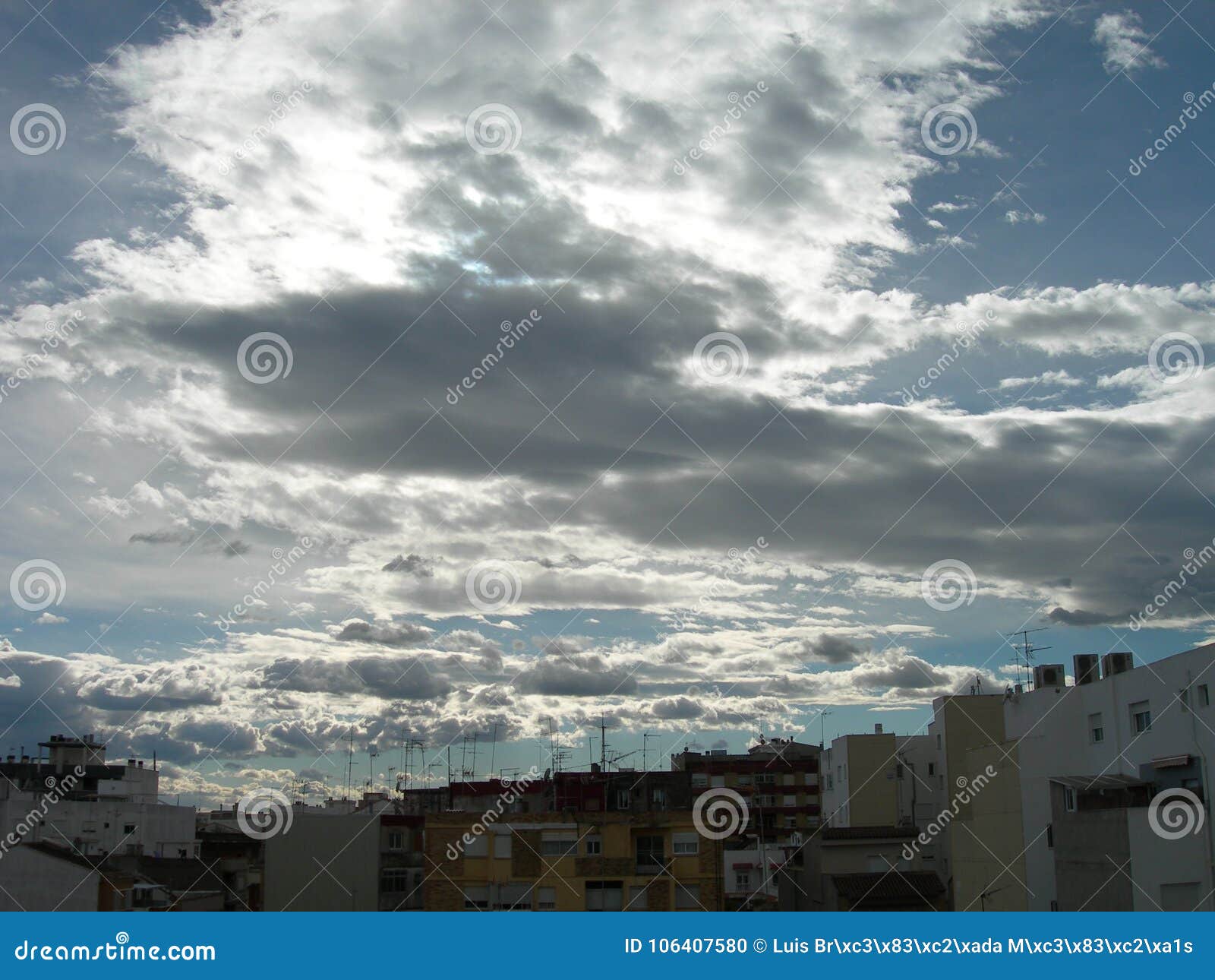 town under a hidden sun and white clouds travelling.evening clouds over the town. ciudad cubierta de nubes