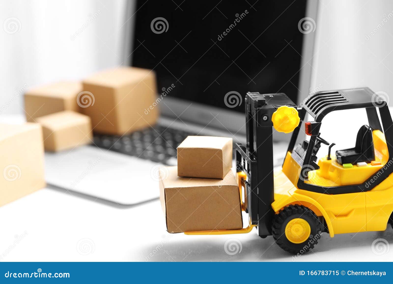 toy forklift with boxes near laptop. logistics and wholesale concept