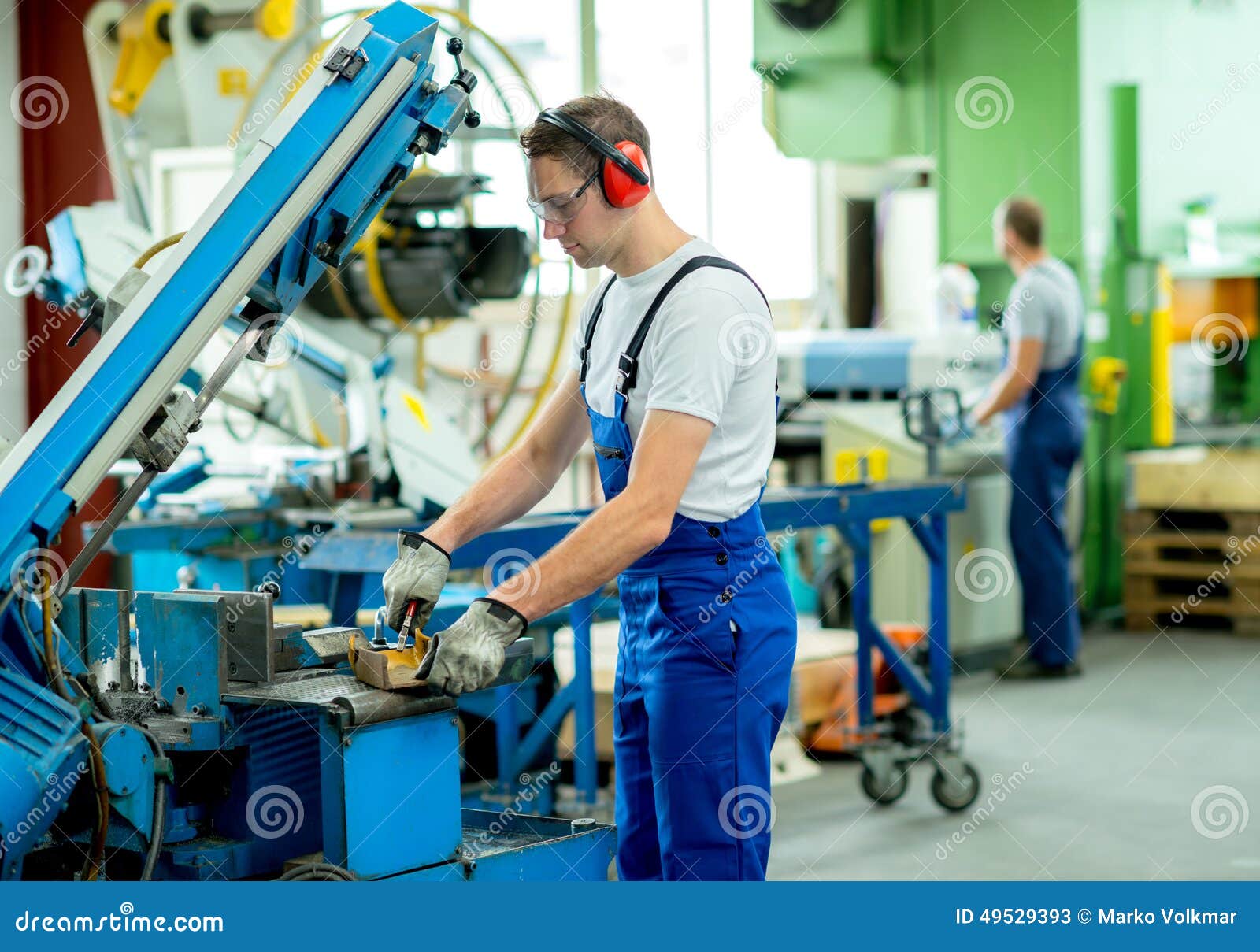 Trabajador en fábrica. Trabajador en ropa protectora en fábrica usando la máquina