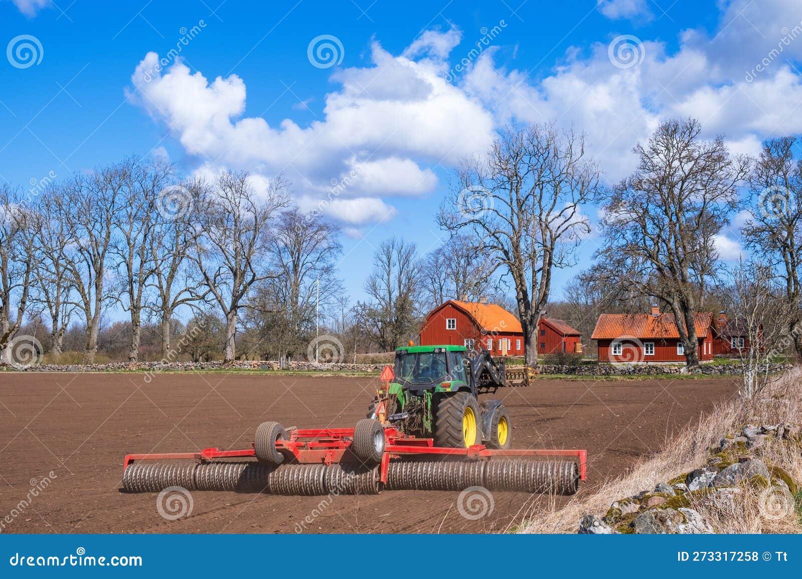 Tractor with a Cultipacker on a Field by a Farm Editorial Stock Photo