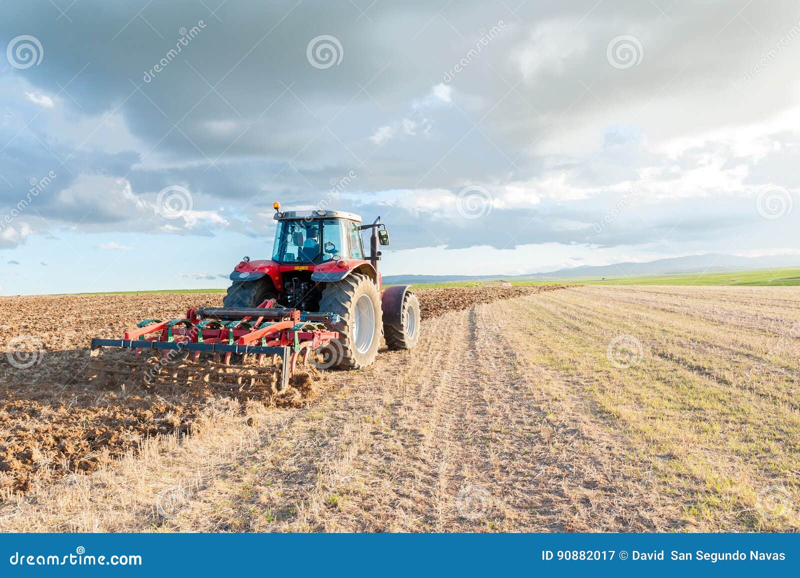 Tractor in the Field in the Foreground with Sky at Sunset Stock Image