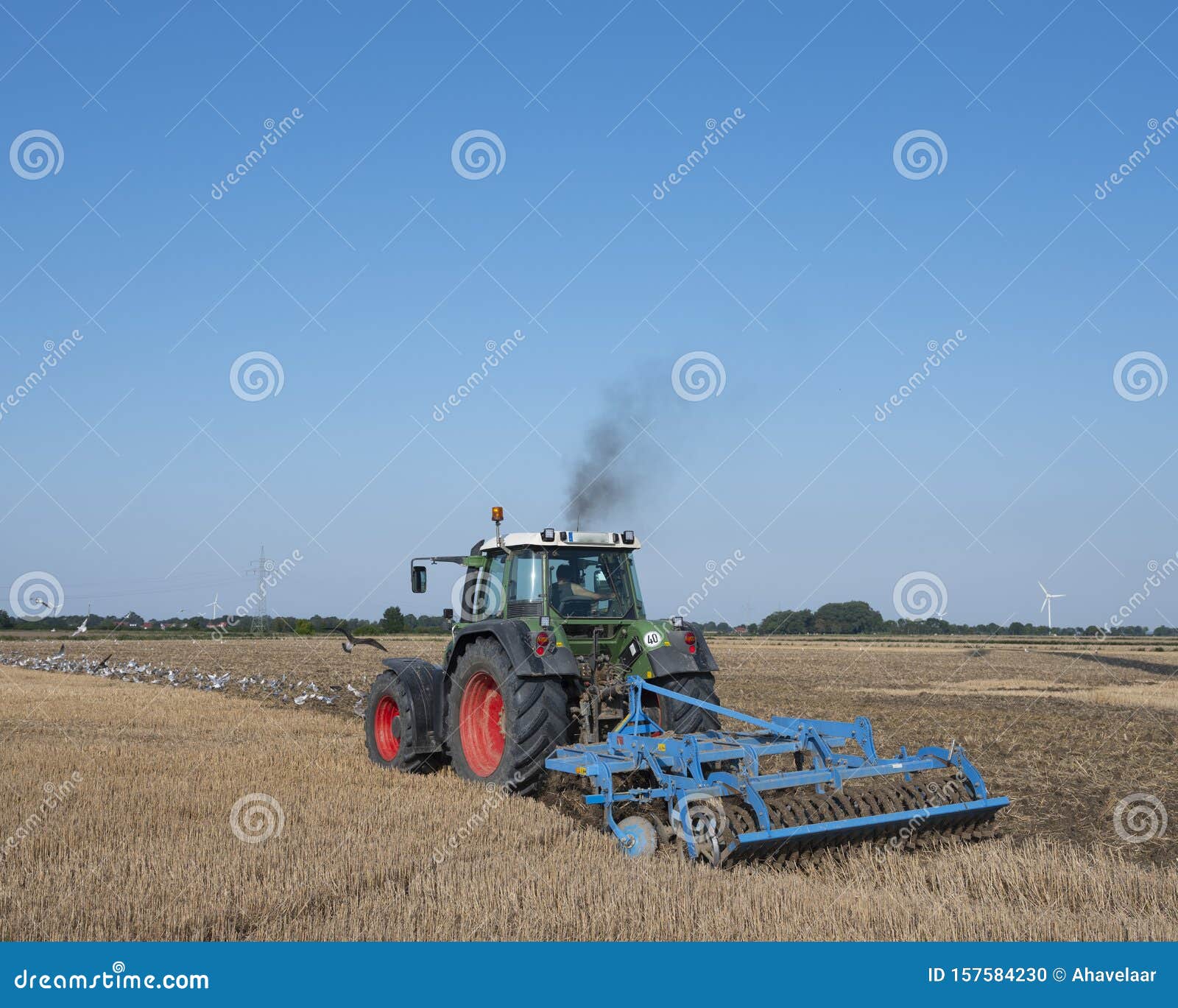 tractor with plow in summer field under blue sky near aurich in germany