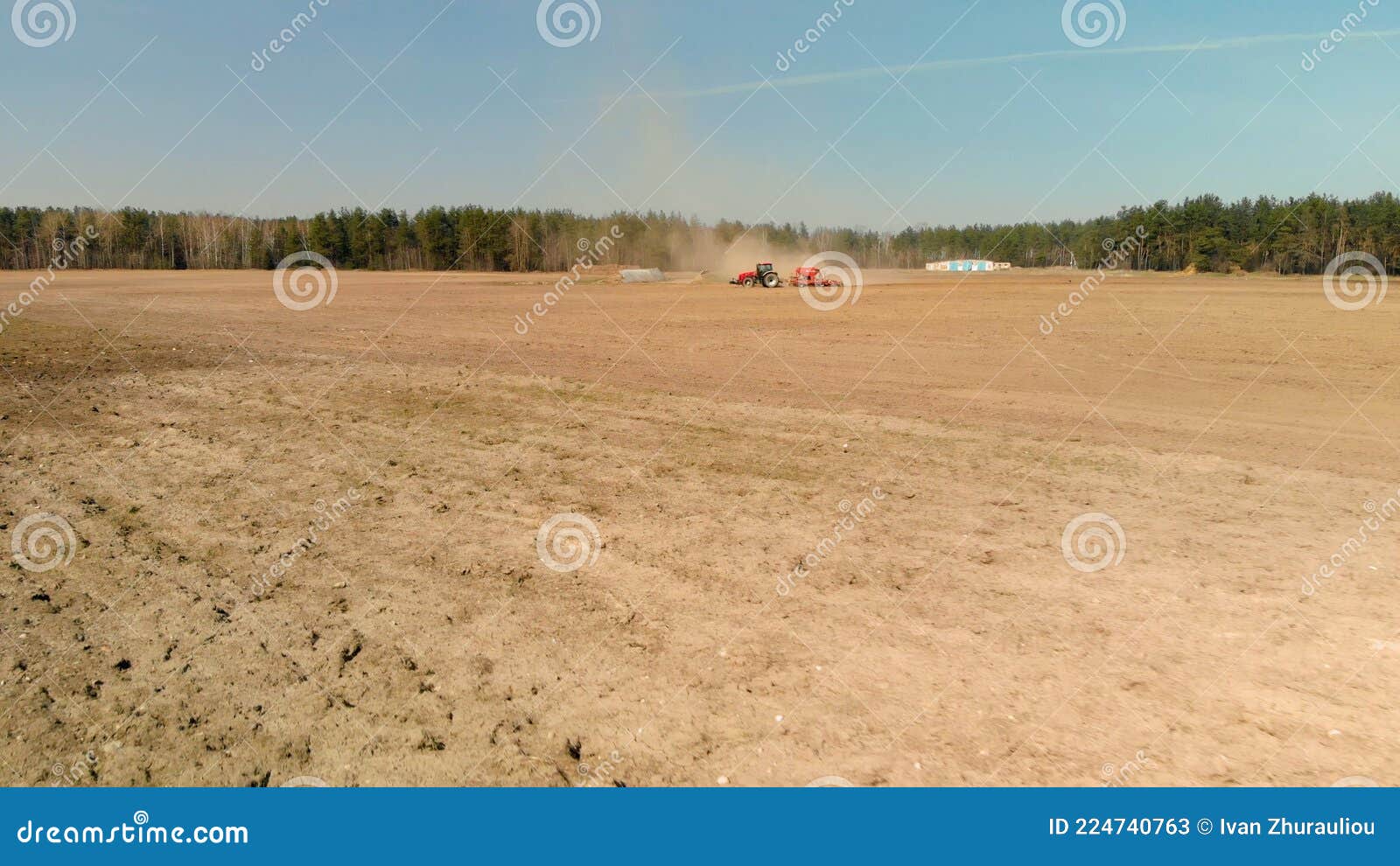 tractor with a seeder is gathering dust on spring farmland