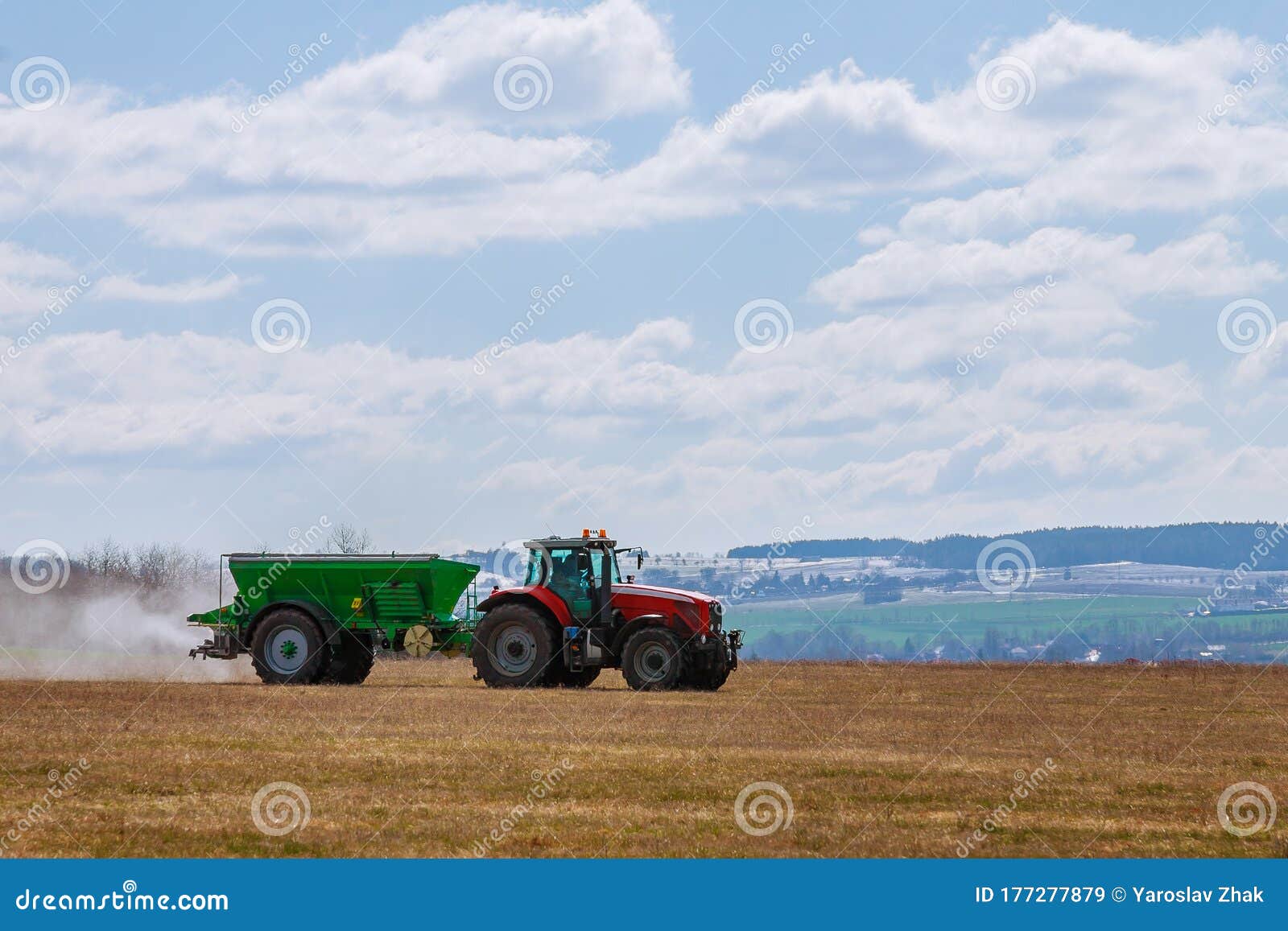 tractor spreading fertilizer on grass field. agricultural work