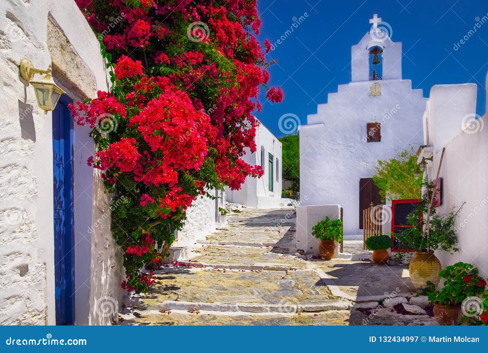 traditional colorful mediterranean street with flowers and church, cyclades, greece