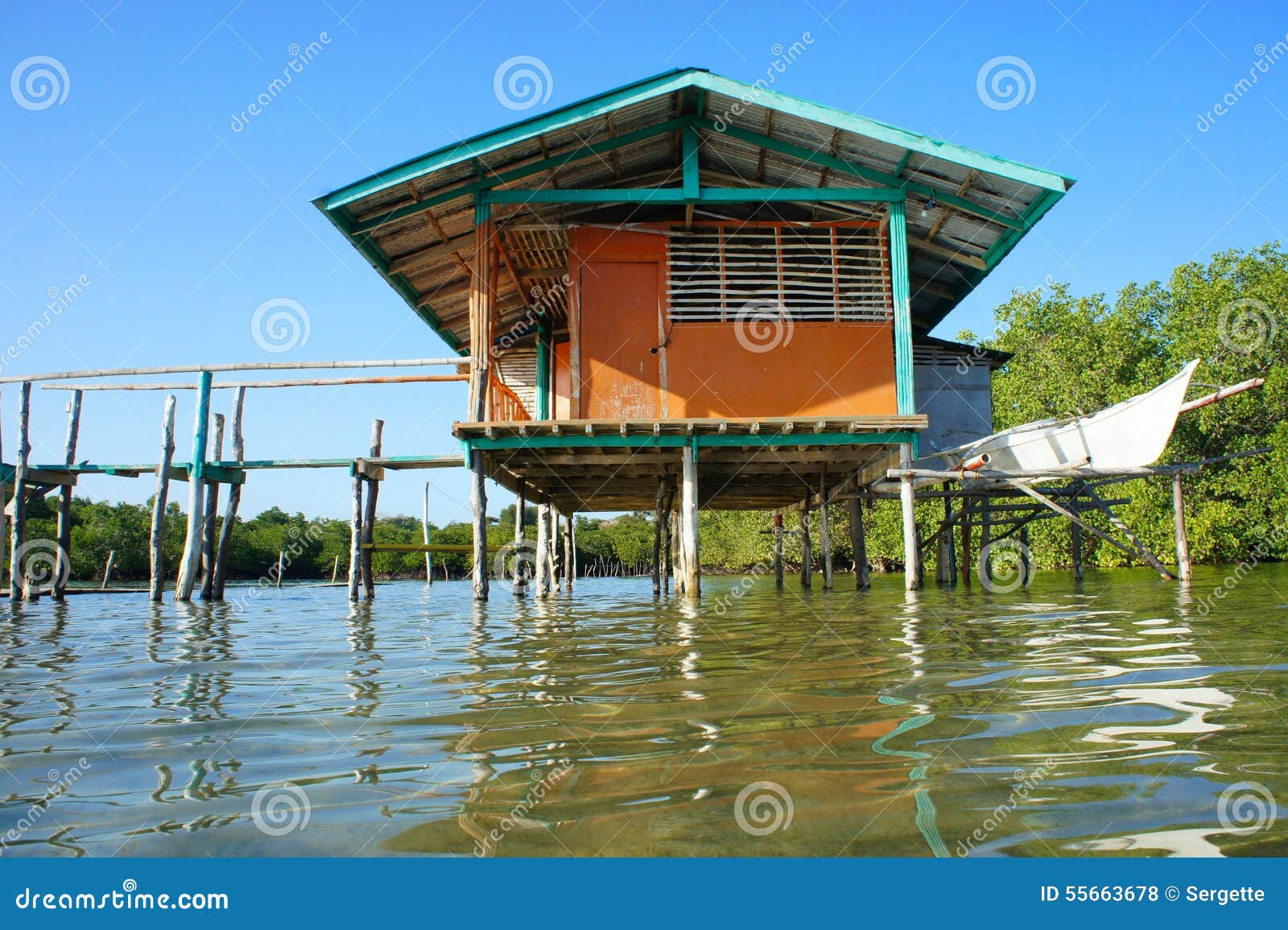 Traditional Stilts House And Boat In Water Under Blue Sky 