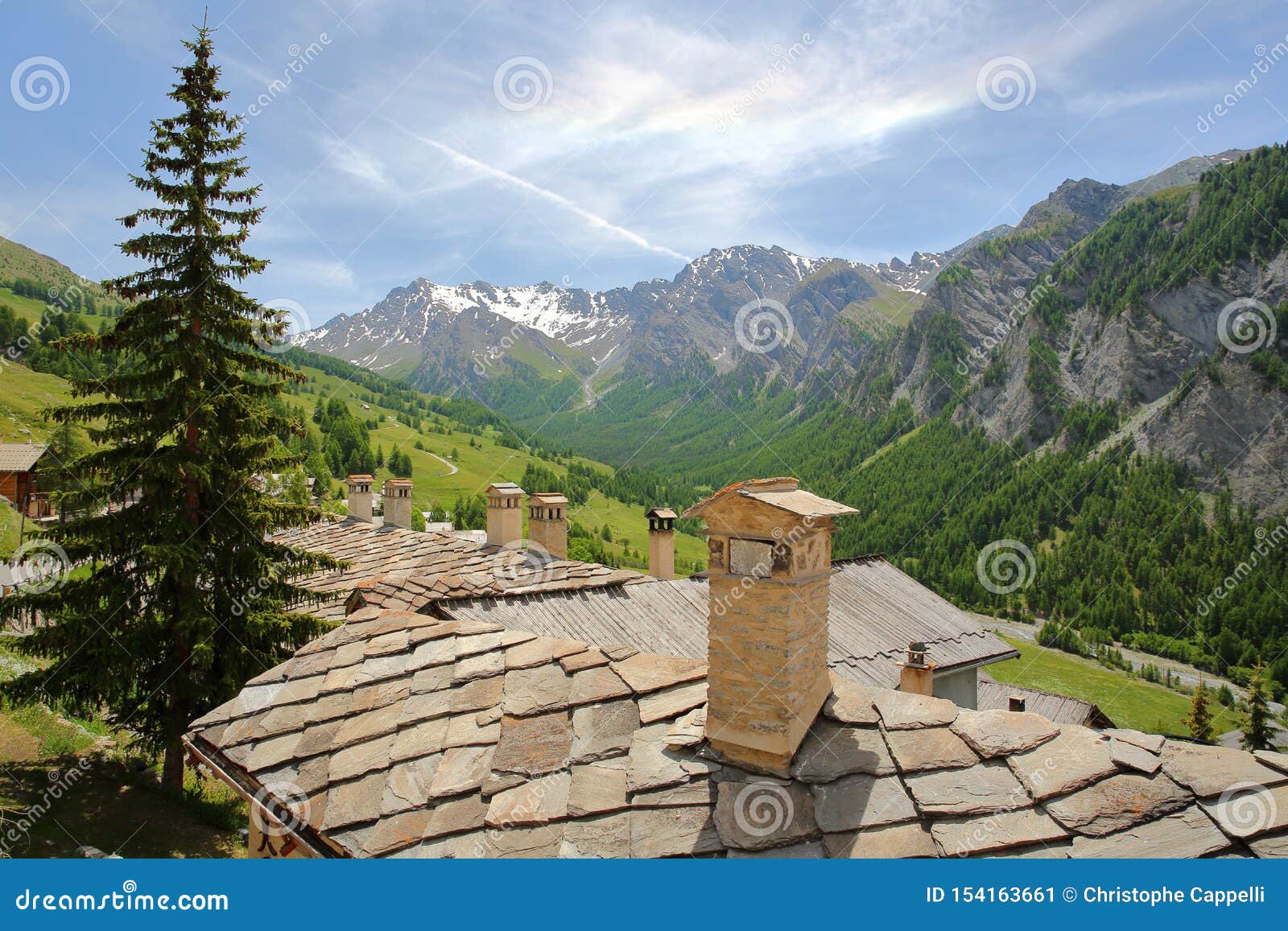 traditional houses roofs and chimneys, with a mountain range in the background, saint veran