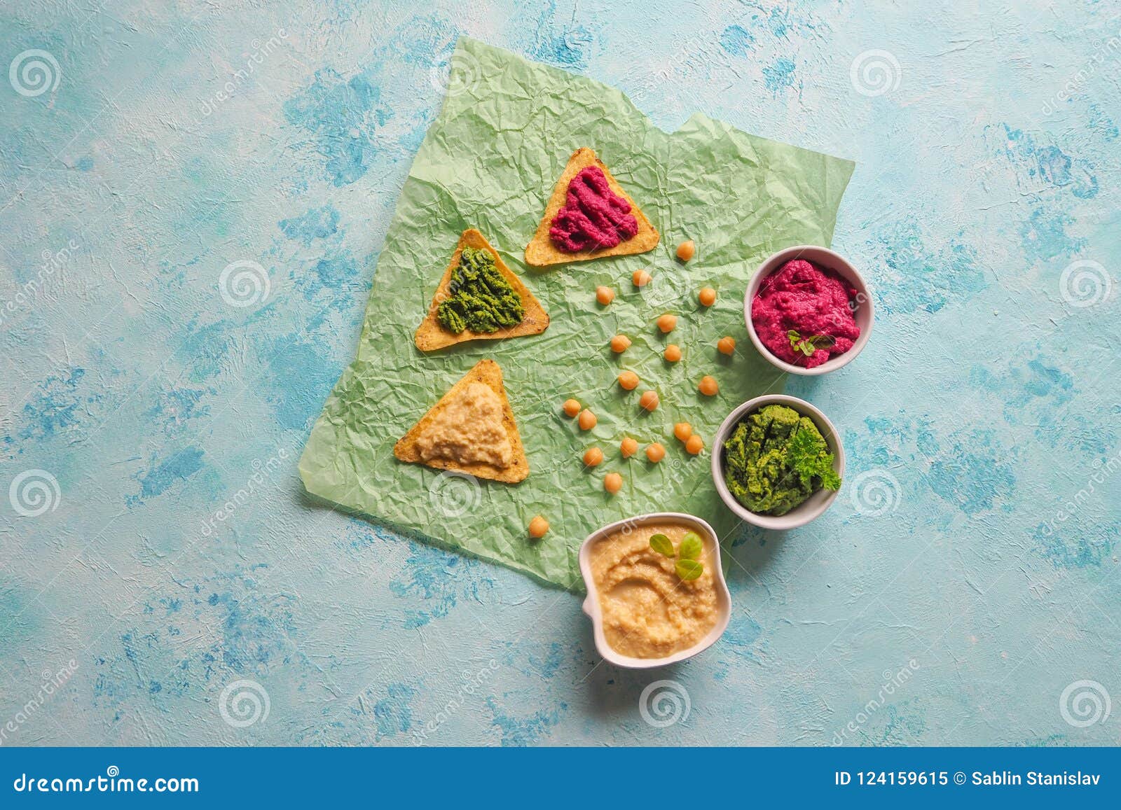 Traditional Hummus Smeared on Corn Chips on a Blue Table. Appetizer of