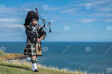 Traditional Scottish Bagpiper in Full Dress Code at the Ocean Stock ...