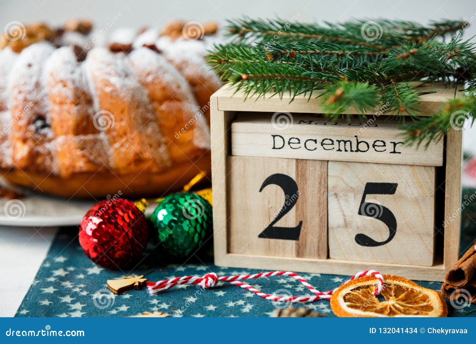 Traditioneller Fruchtkuchen für Weihnachten verziert mit Puderzucker und Nüssen, Rosinen nahe bei hölzernem Kalender mit Datum am 25. Dezember selbst gemachtem Gebäck Delicioius Neues Jahr und Weihnachtsfeierkonzept