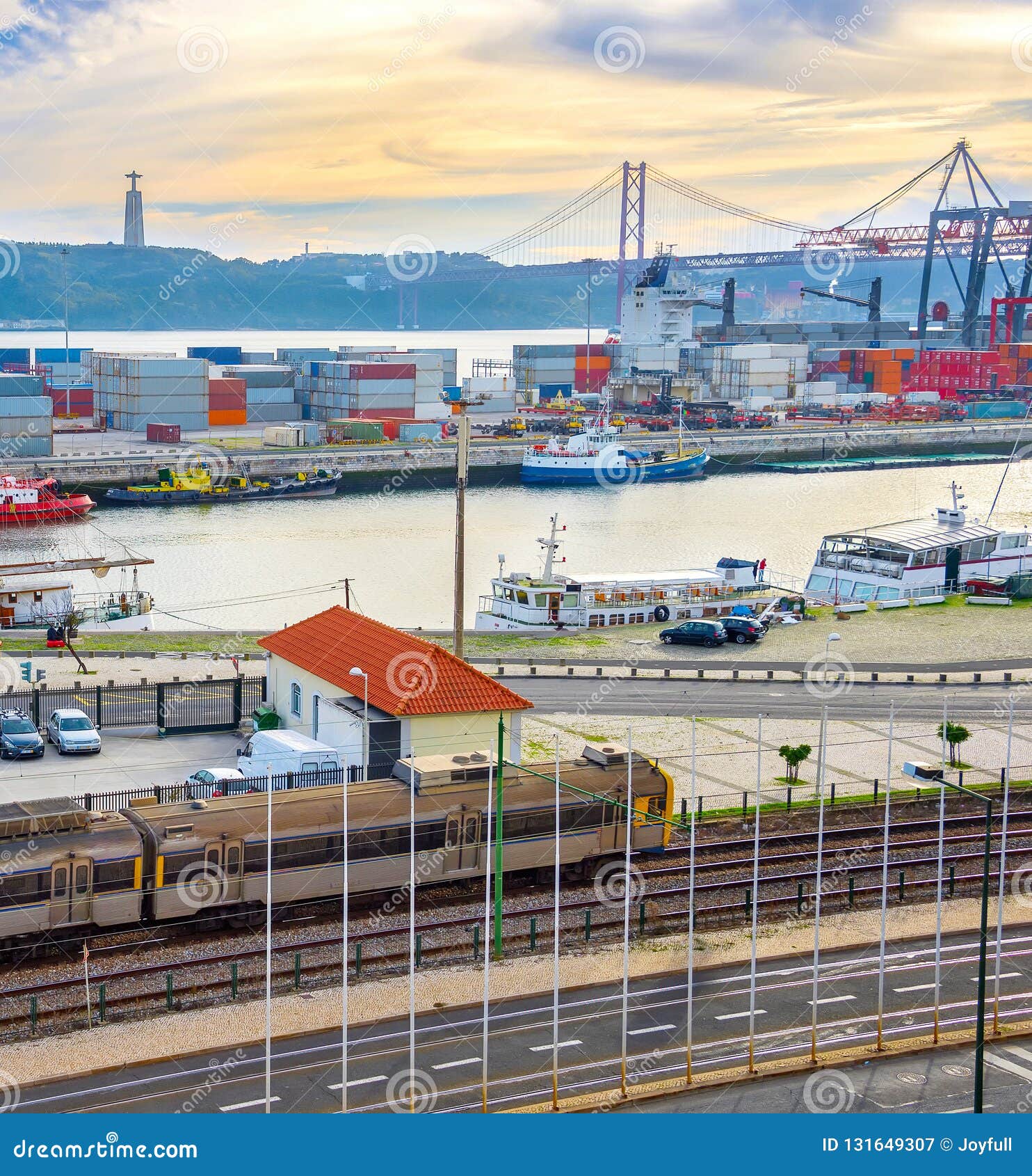 train on railroad by comercial port with ships and containers, 25 de abril bridge over tagus river at sunset, christ the king