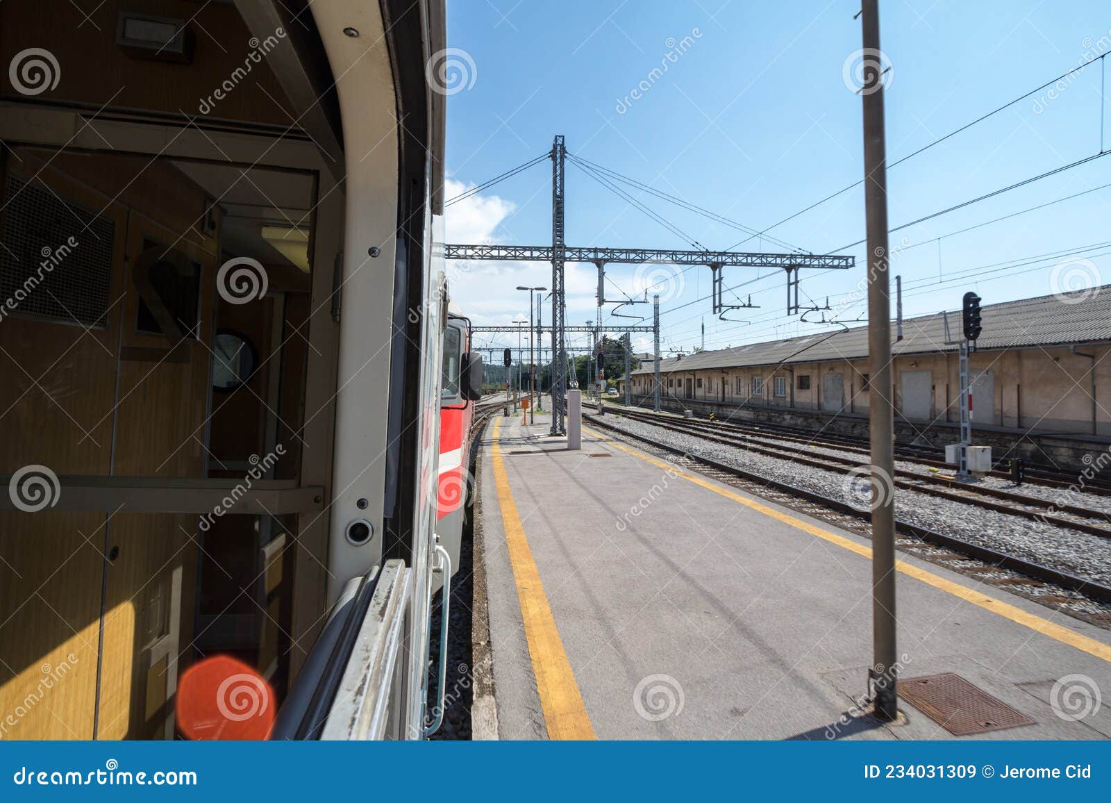 train station platform of pivka, slovenia, seen from the window of a passenger train travelling accross europe during sunny summer
