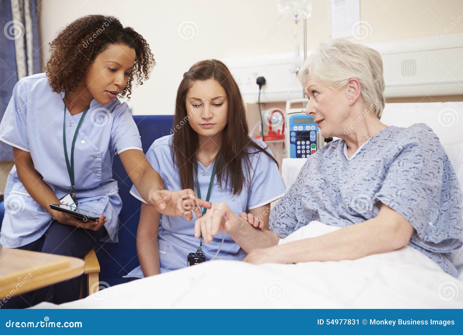 trainee nurse sitting by female patient's bed in hospital